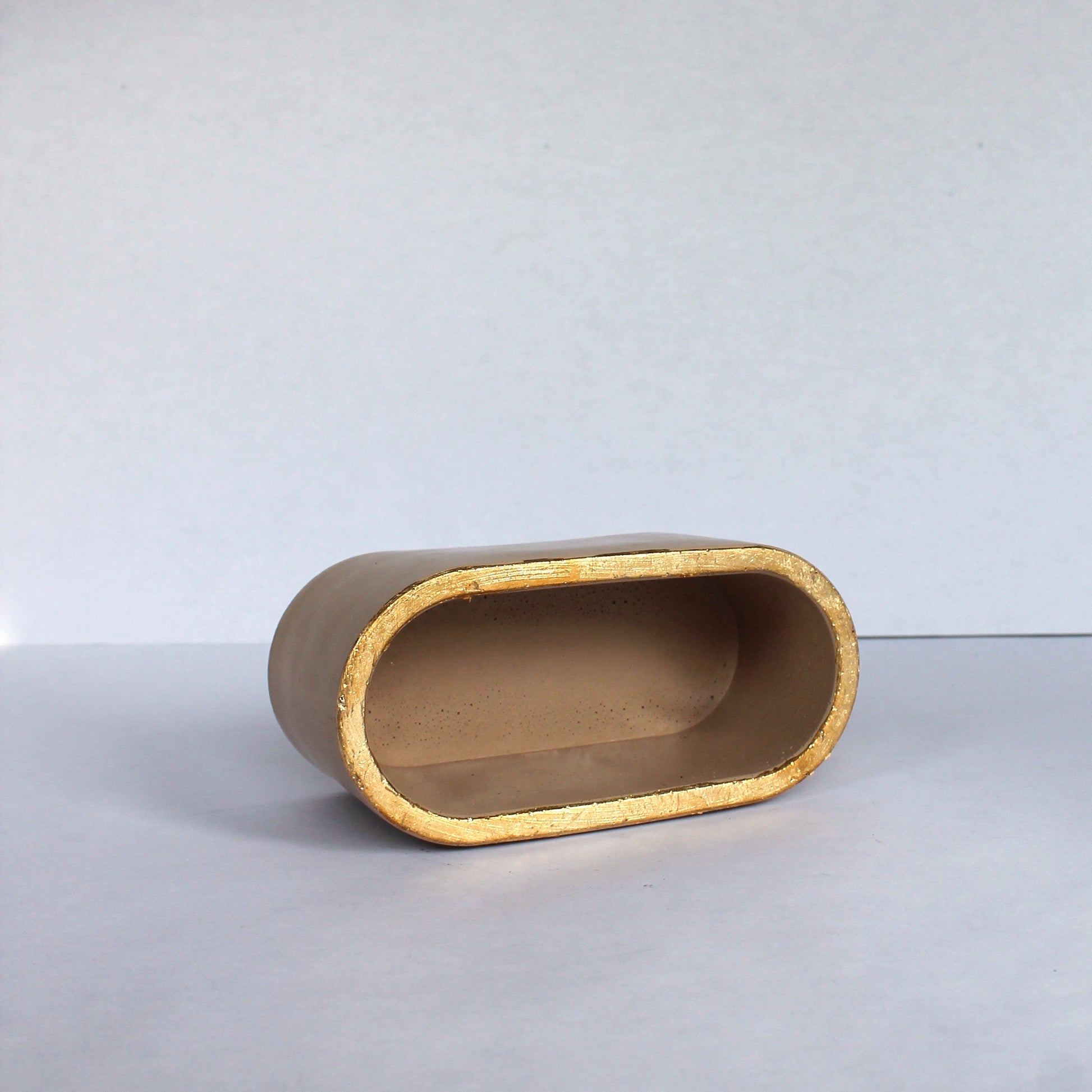 beige oval concrete object on a white surface with a white background