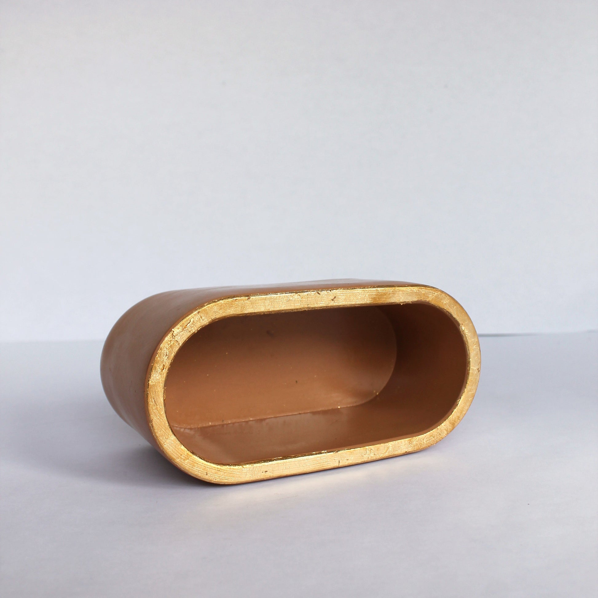 Cylindrical concrete object with gold rim on a white background