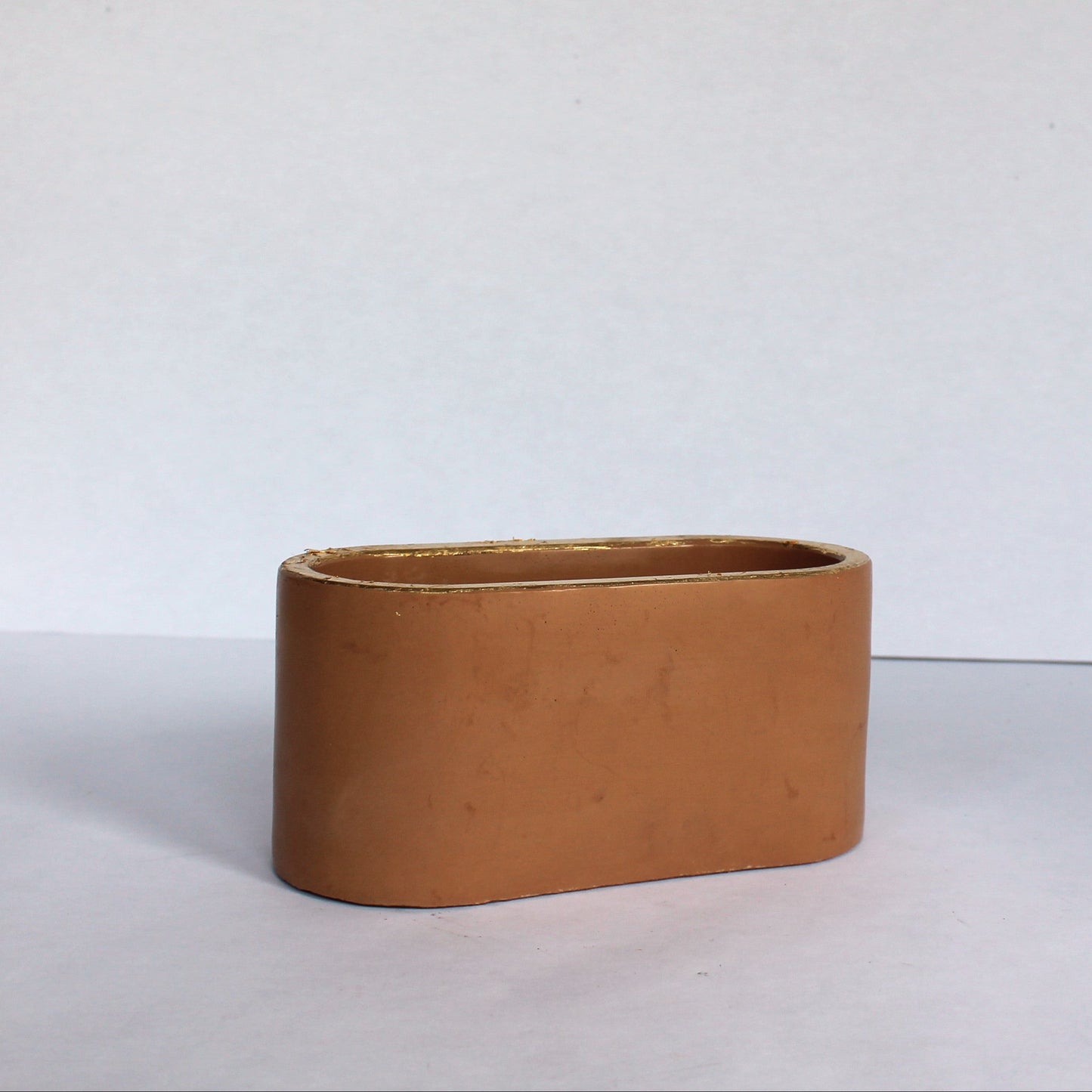 Clay colored oval planter on a white background