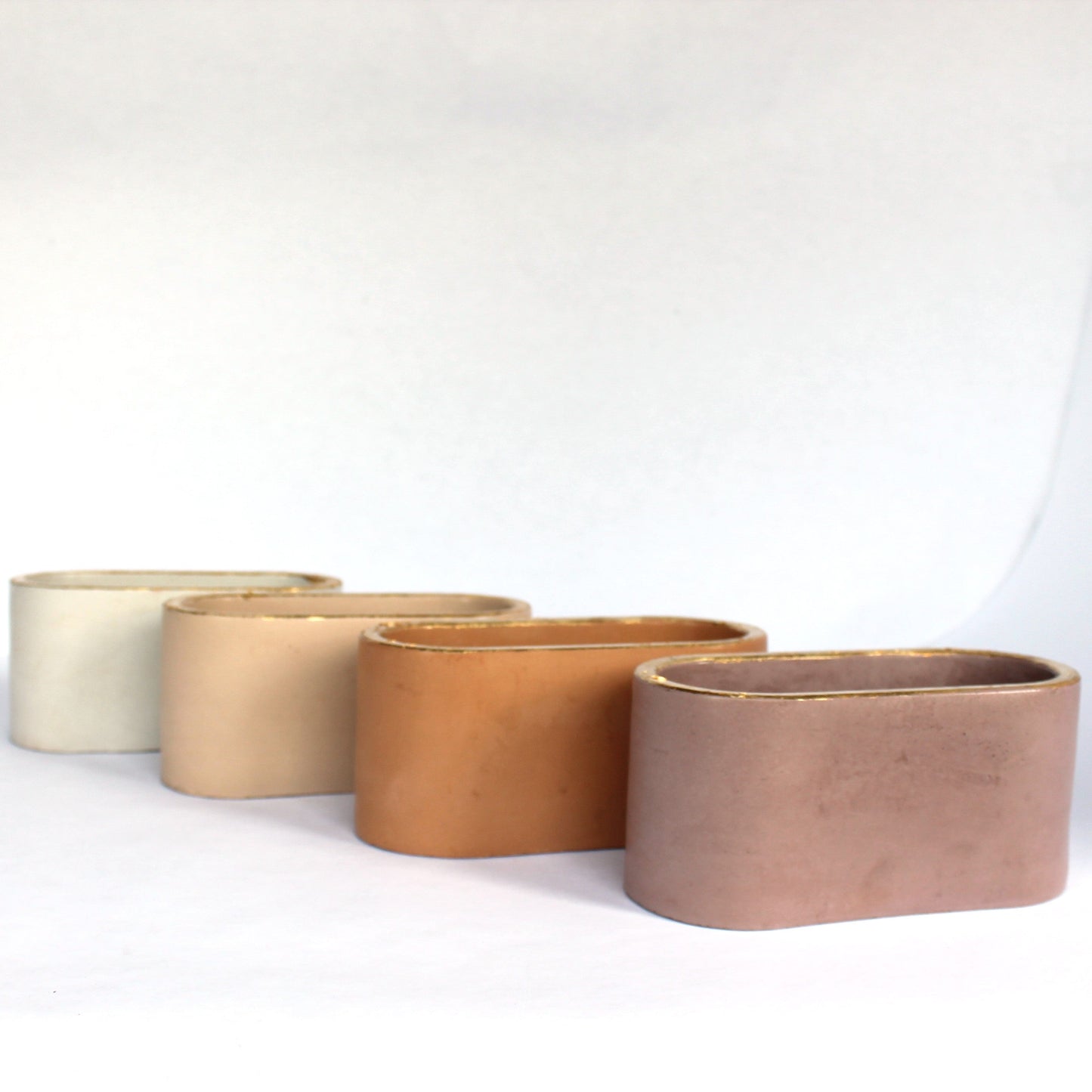Set of four concrete pots in different colors on a white background