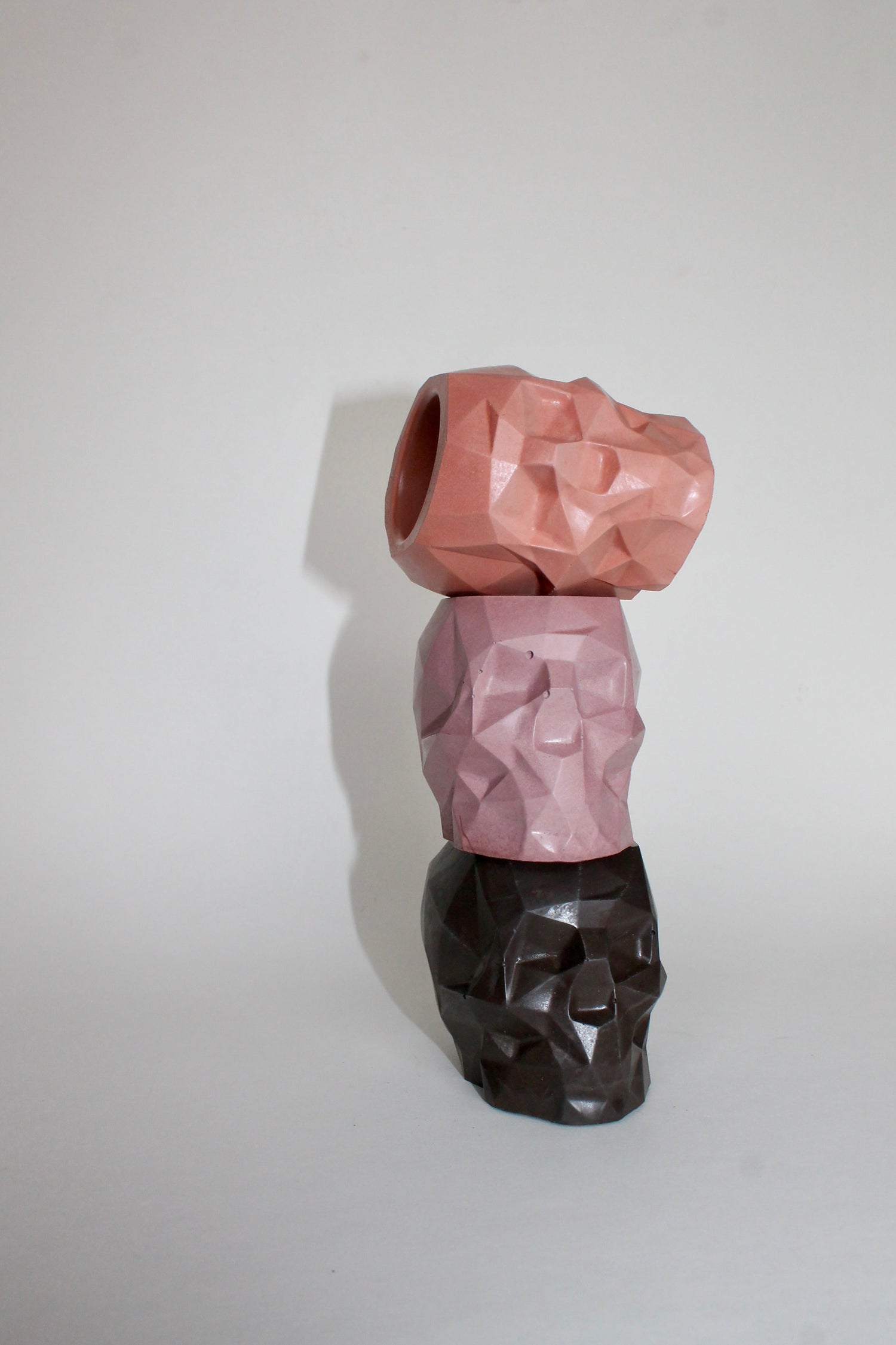 three stacked concrete skulls in orange, pink and black