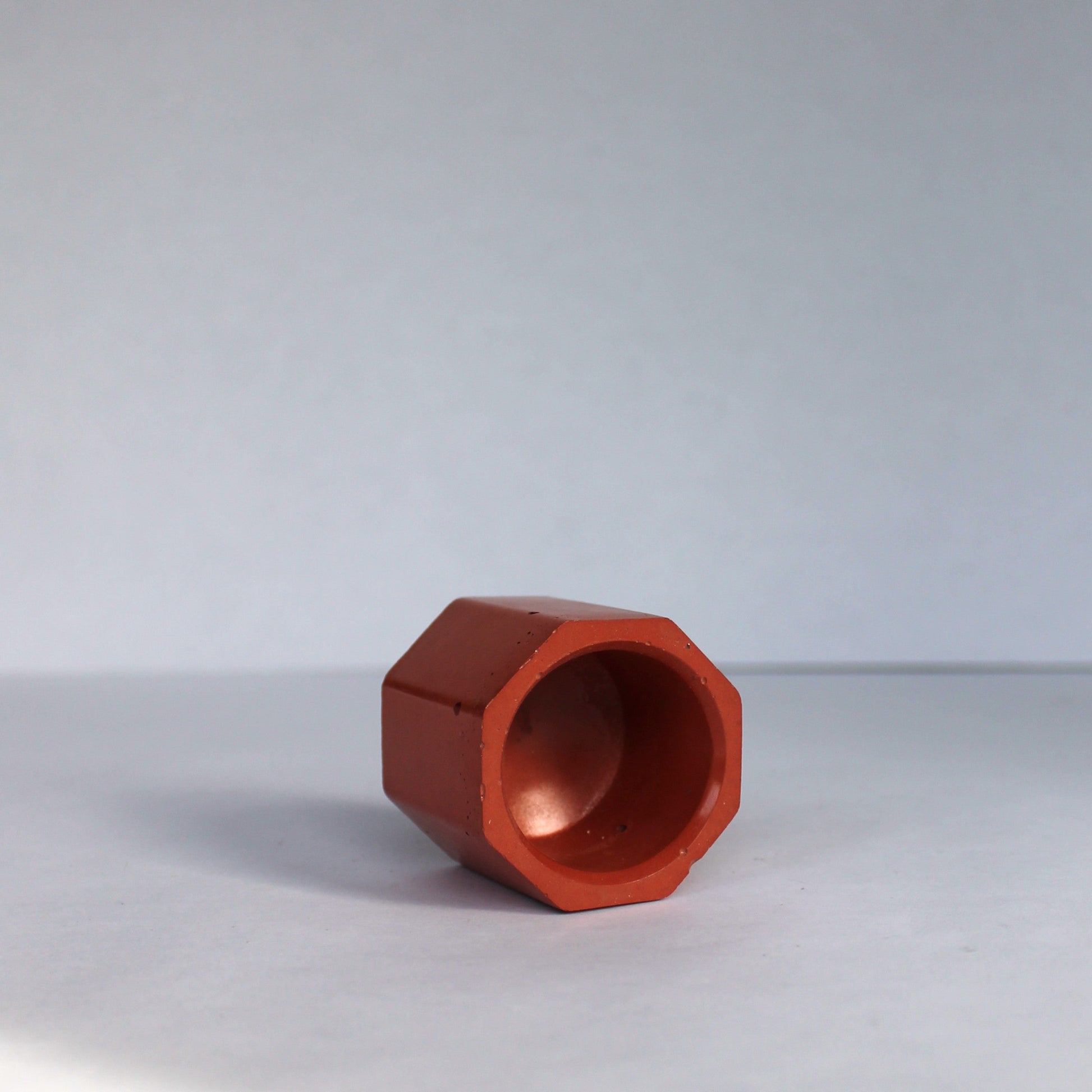 orange geometric object on a white surface with a white background