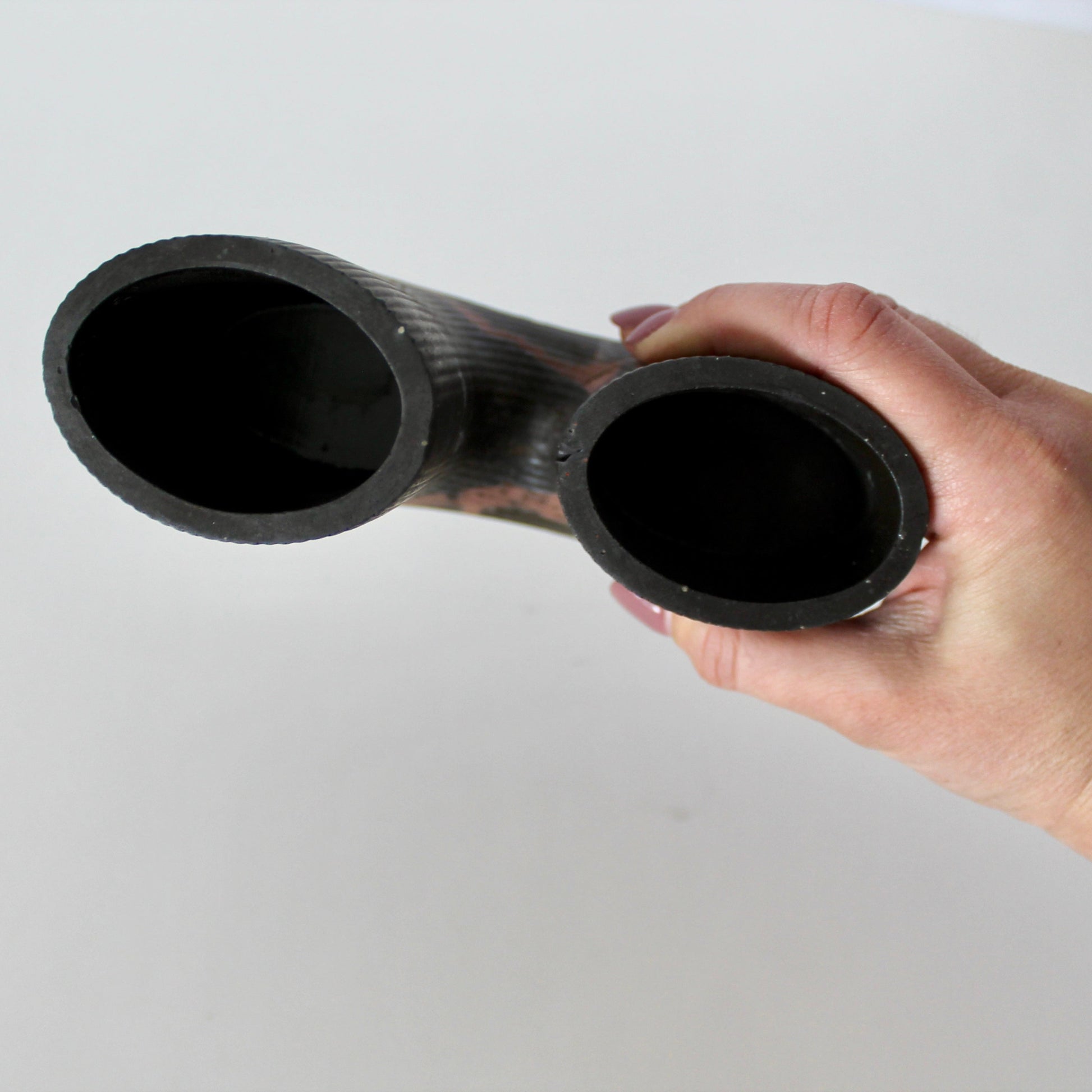 Hand holding a black double-ended vaes against a white background