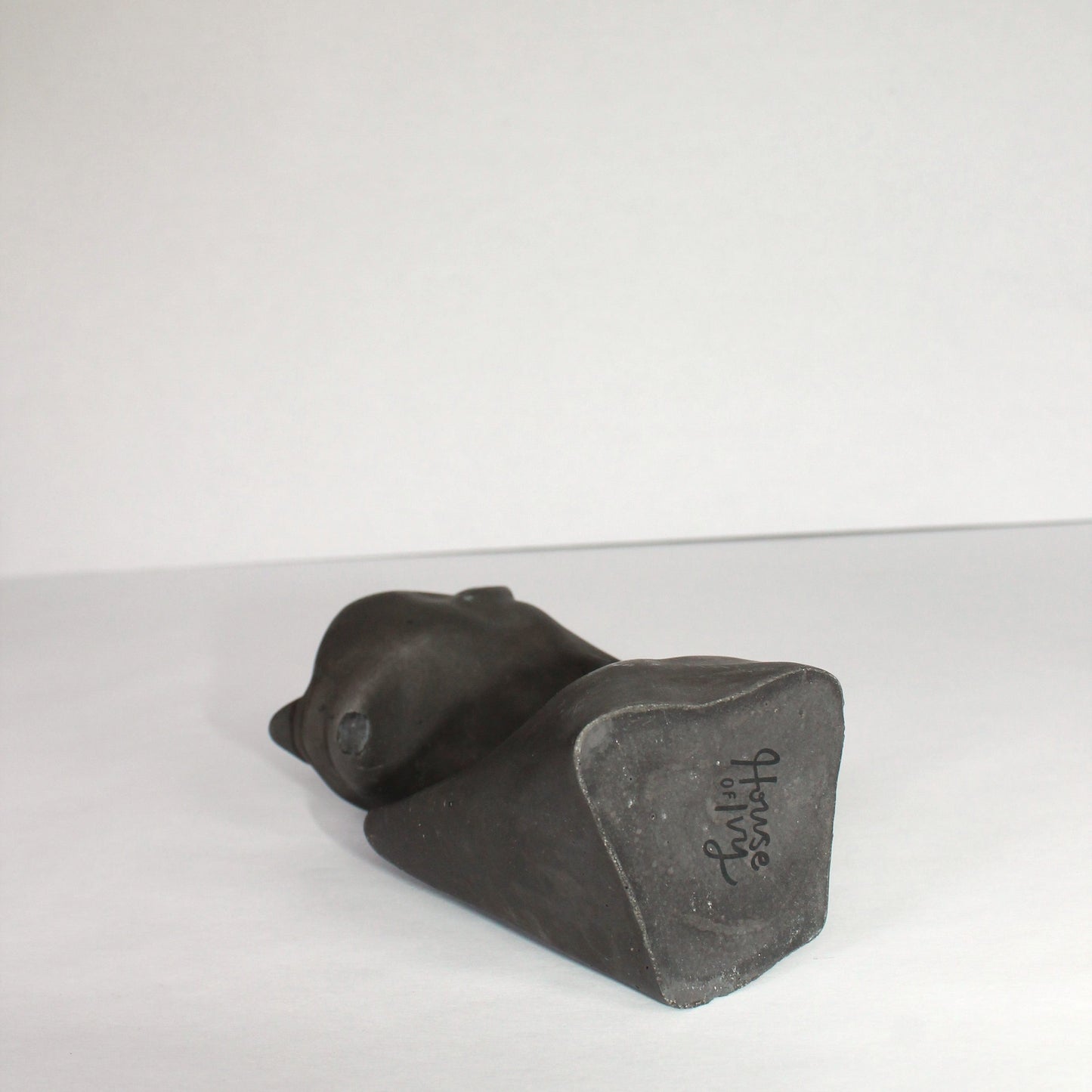 Black concrete sculpture on a white surface with a white background