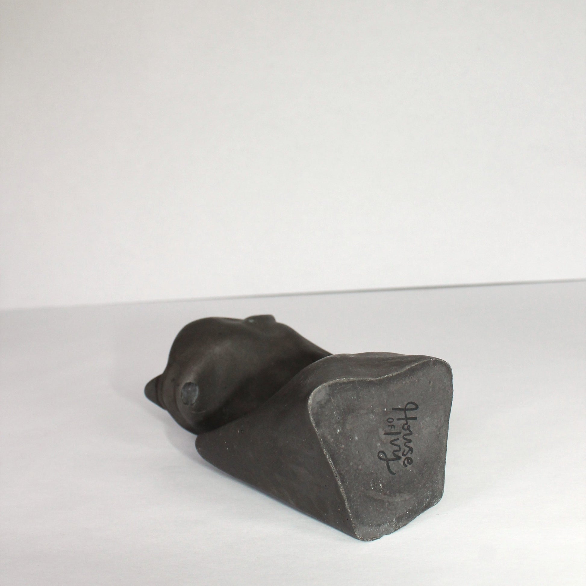 Black concrete sculpture on a white surface with a white background