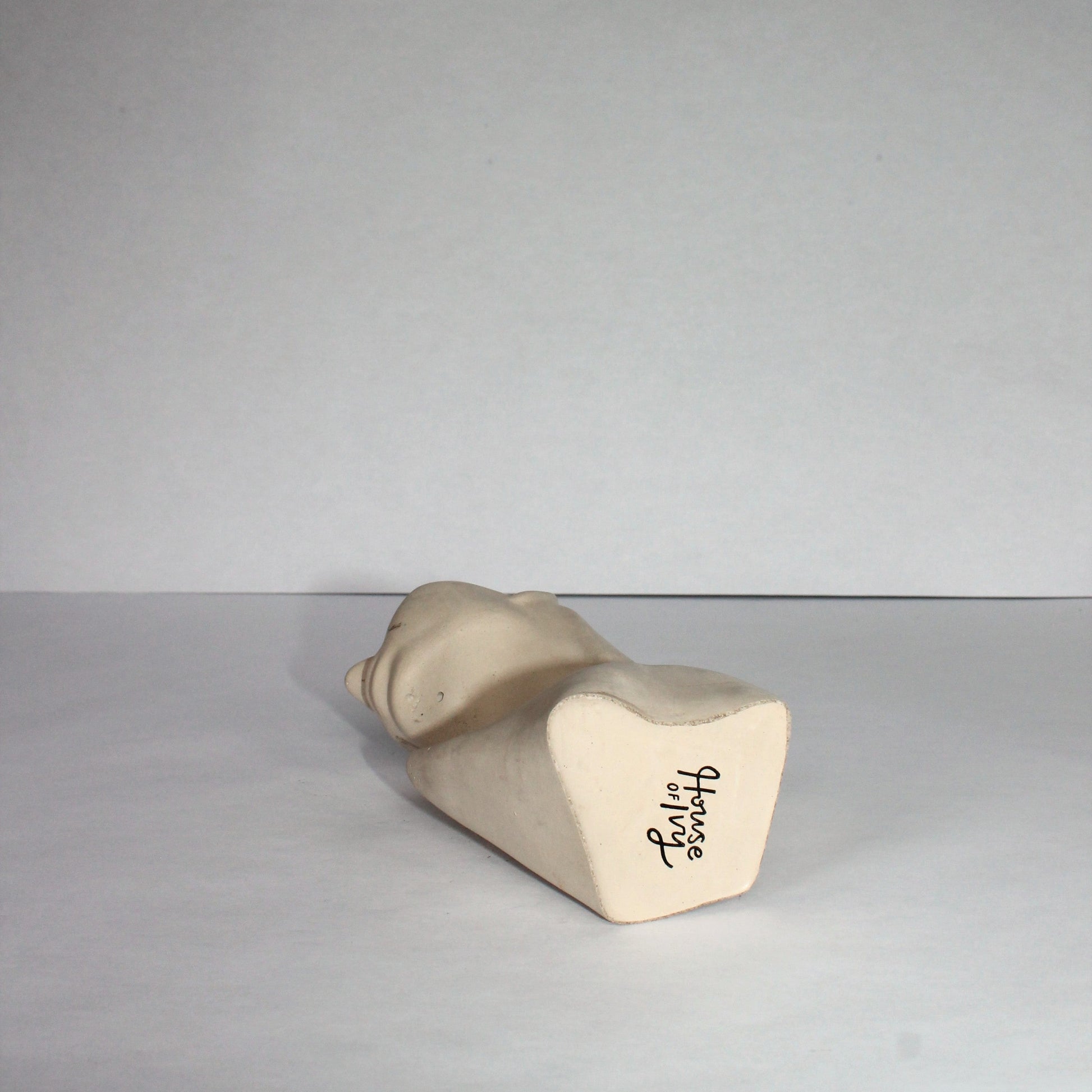 concrete sculpture of a female silhouette lying down on a plain background