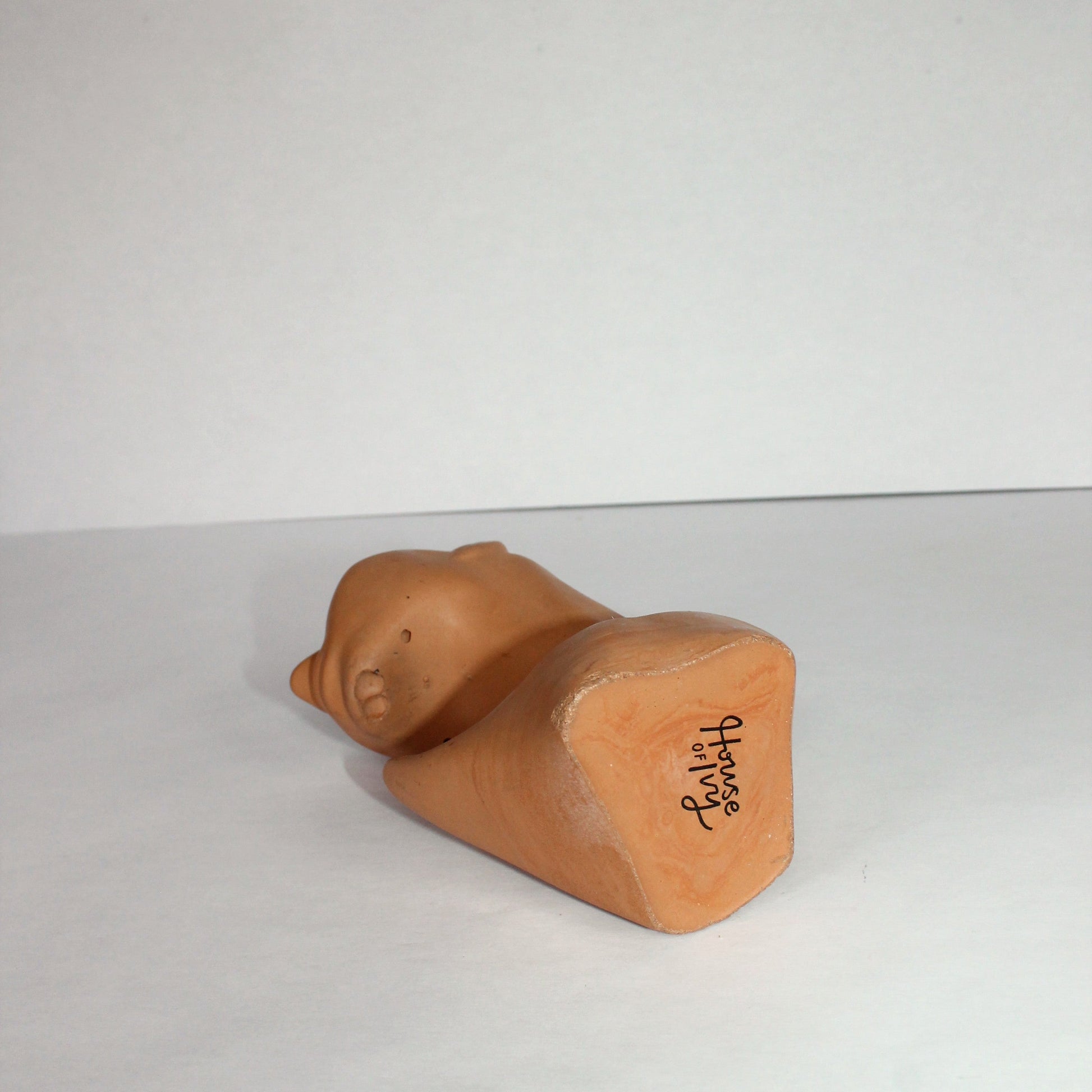 Terracotta-colored body-shaped object on a white surface with a plain background