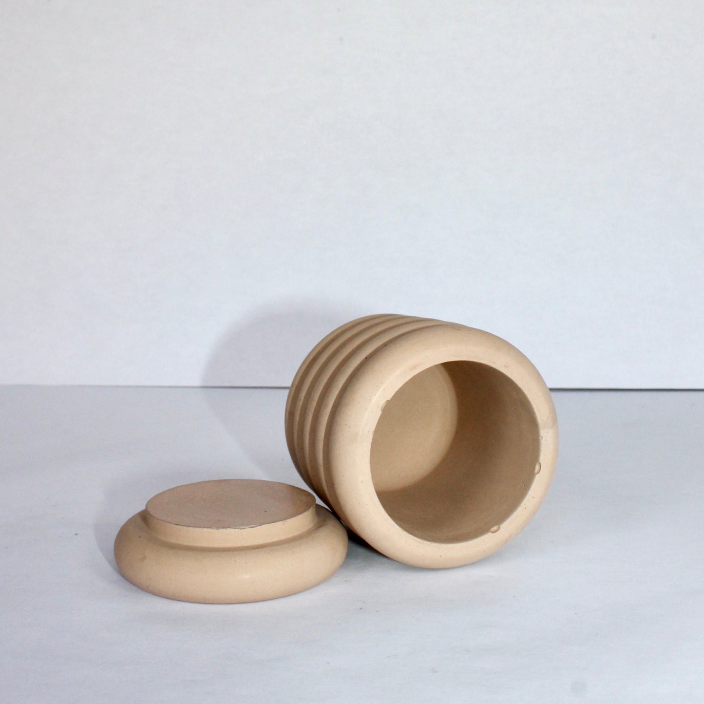 inside view of a beige concrete jar with lid on a white background