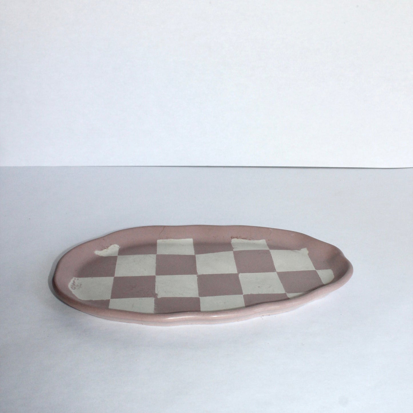 Pink checkered cement plate on a white background