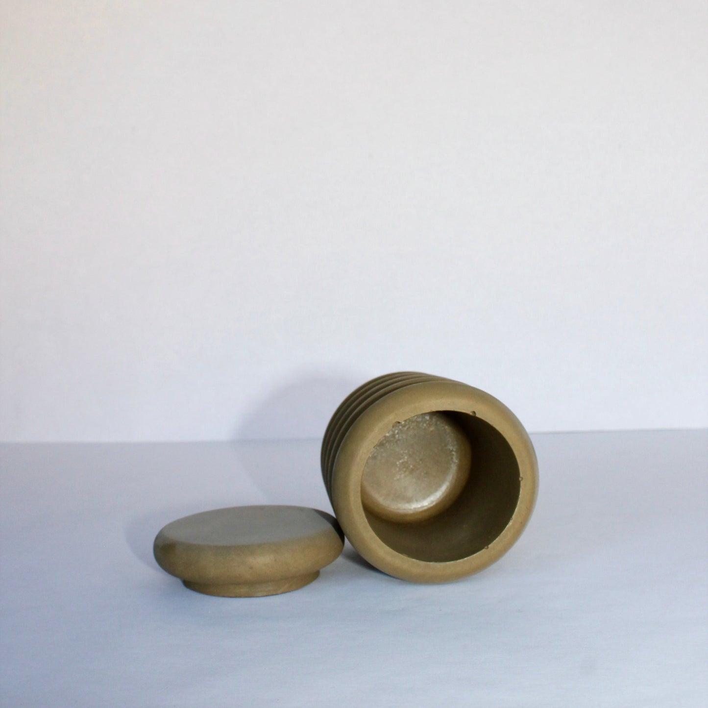 Dark green concrete jar with lid on a white background
