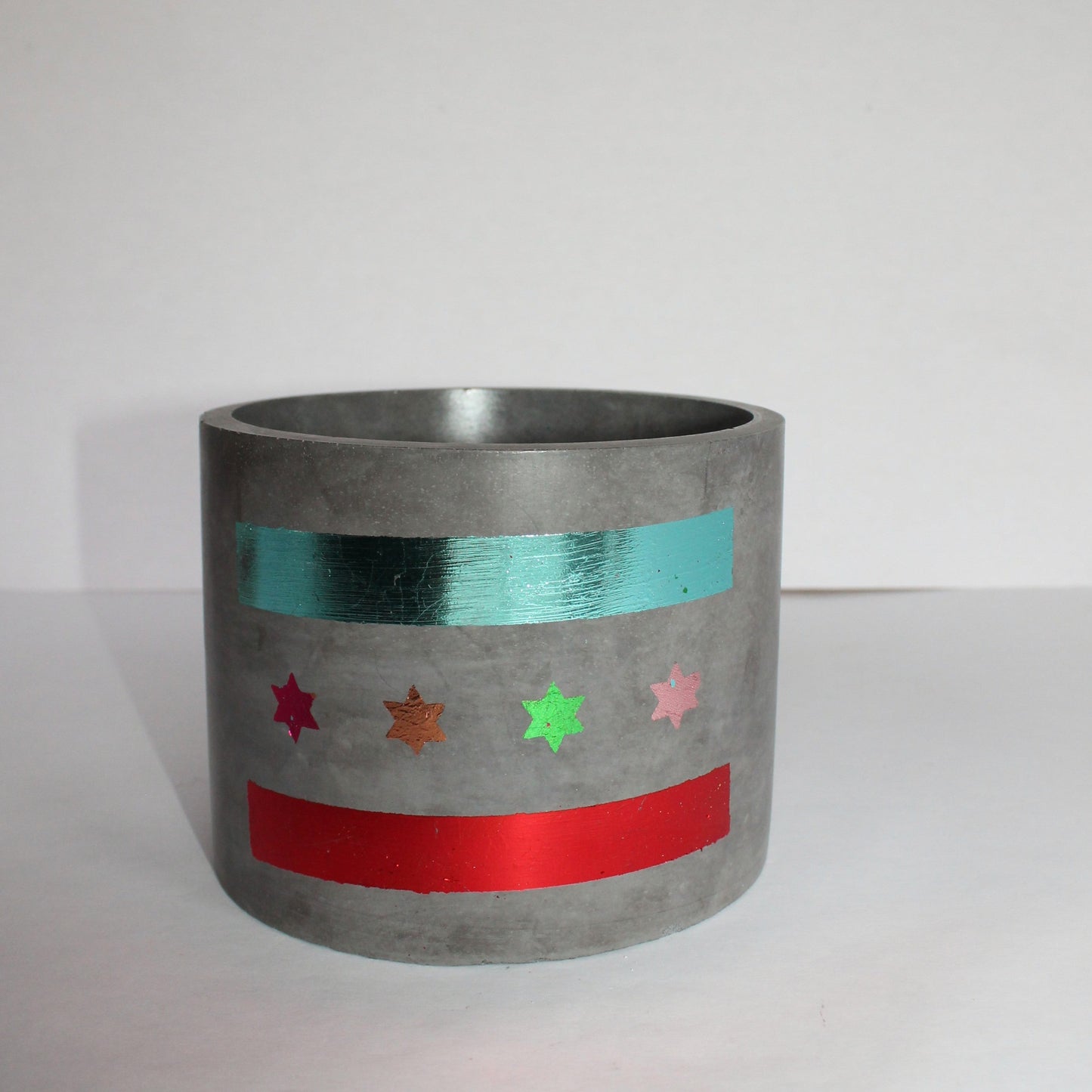 Cylindrical concrete planter with colorful Chicago flag design on a white background