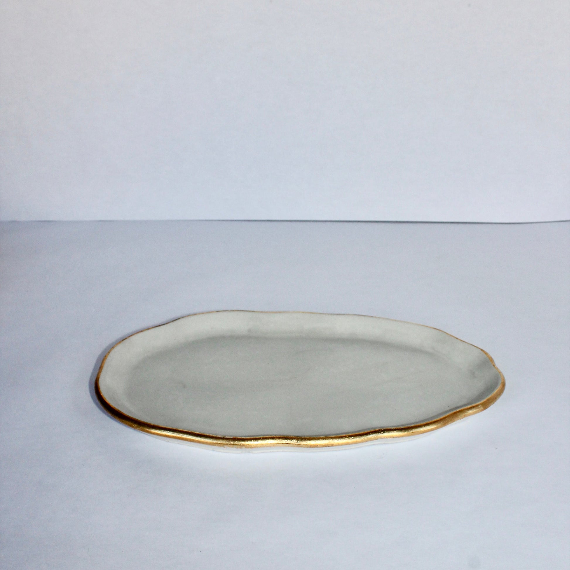 Gray concrete plate with gold rim on a white background