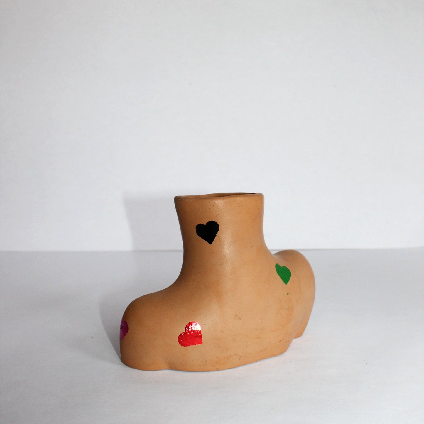 concrete vase with colored hearts on a white background