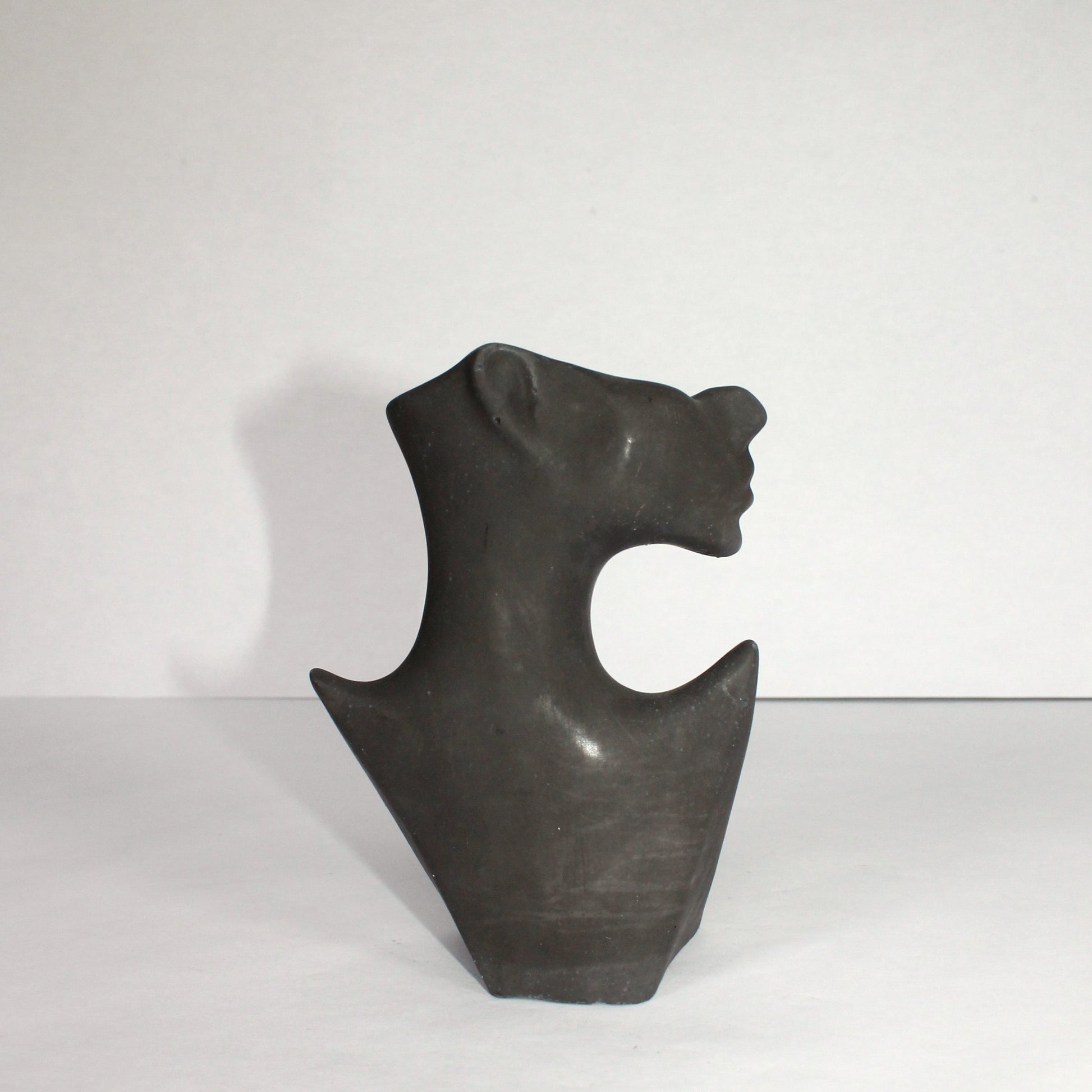 Black concrete sculpture of a face on a white background