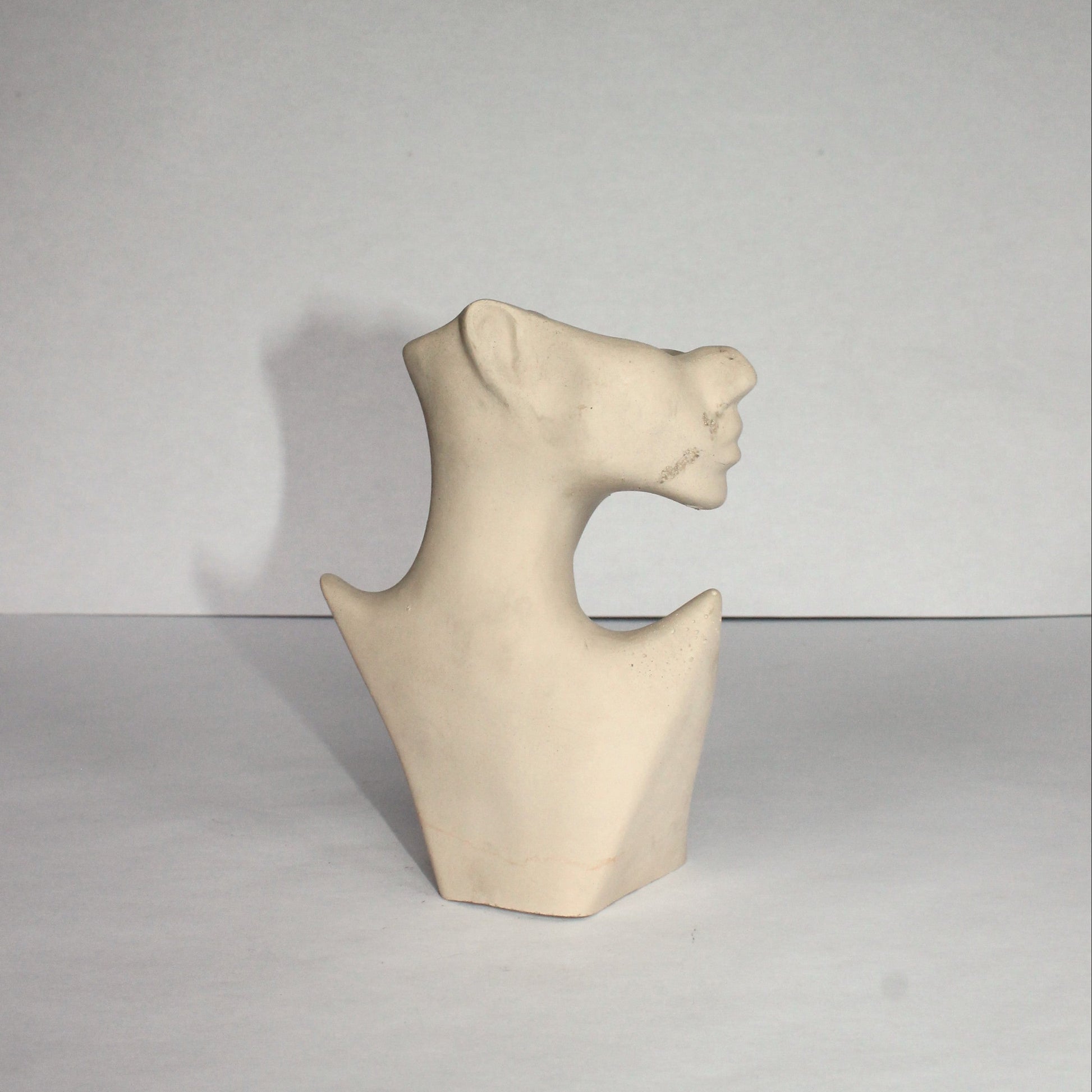 gray concrete sculpture of a face on a plain background