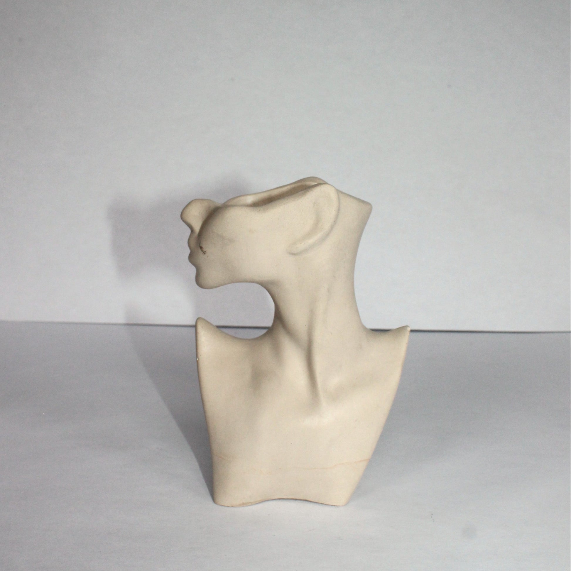 light gray sculpture of a abstract figure on a white background