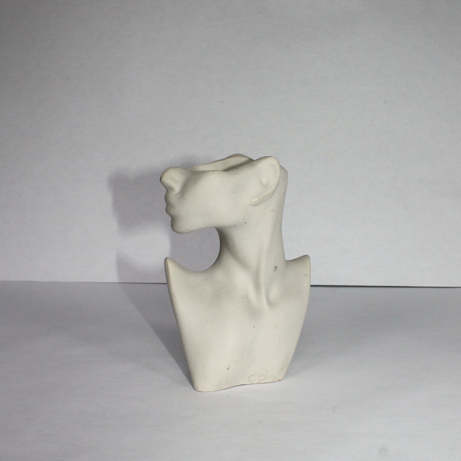 light gray sculpture of a bust on a white background