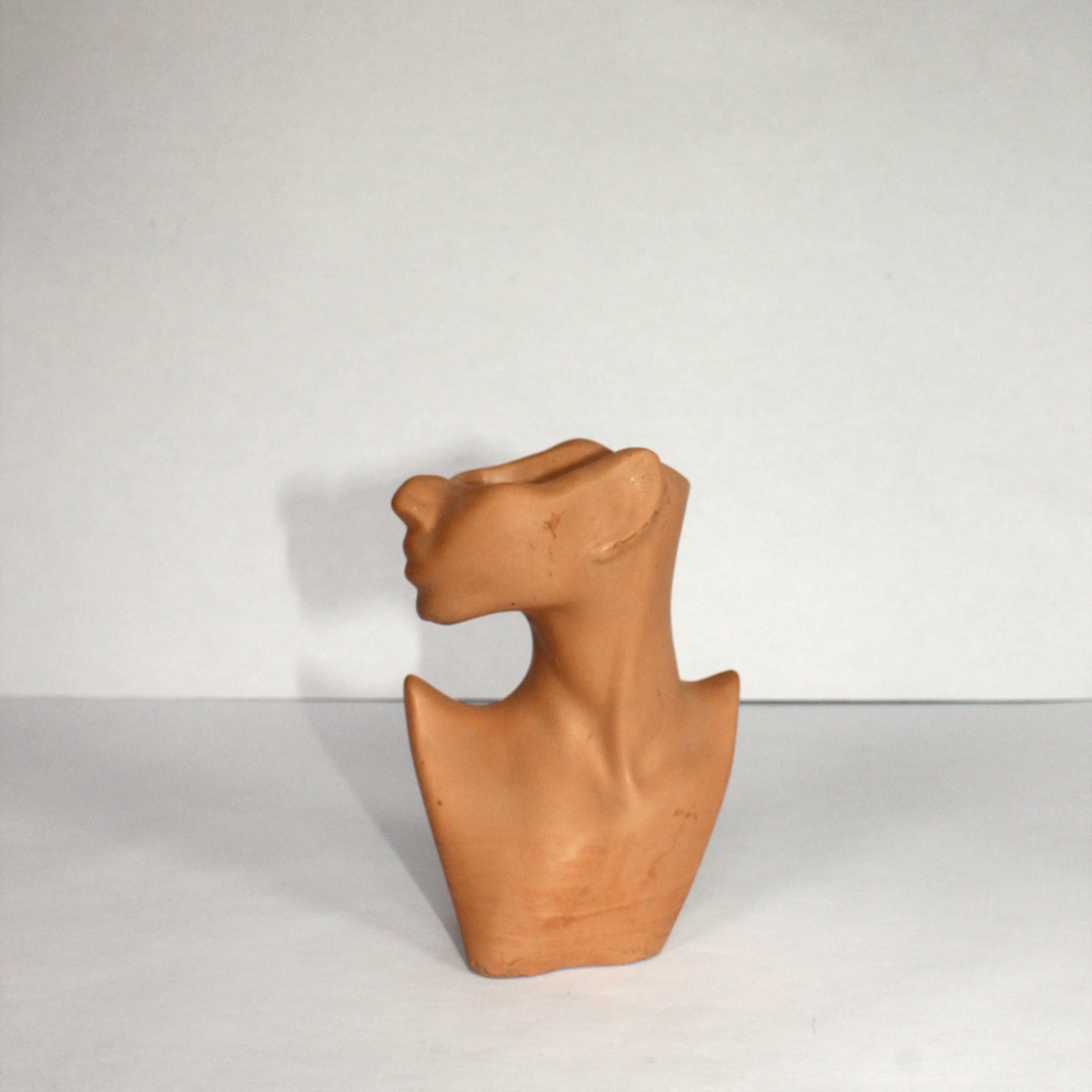 terracotta abstract woman sculpture on a white background