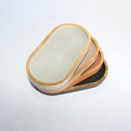 Stack of oval concrete dishes with gold rim on a white background