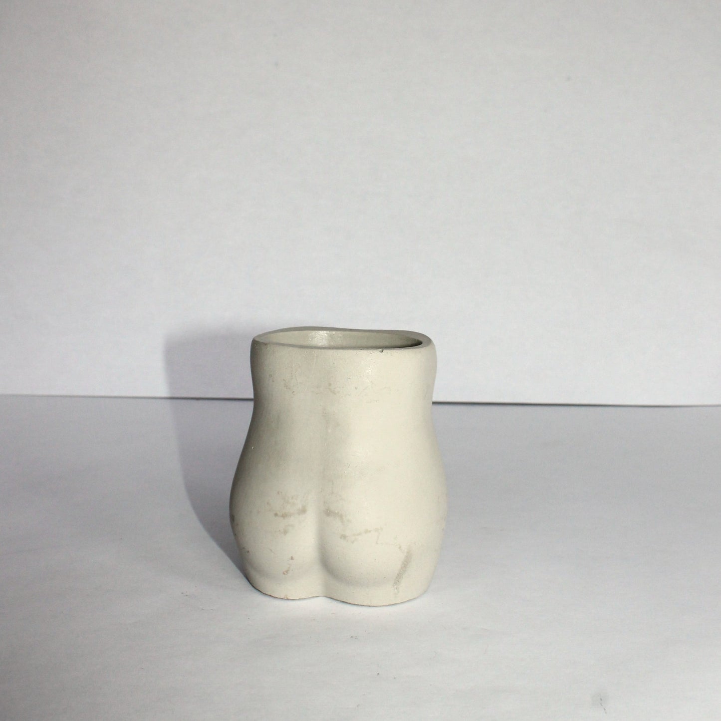 Concrete vase shaped like a female torso on a white background