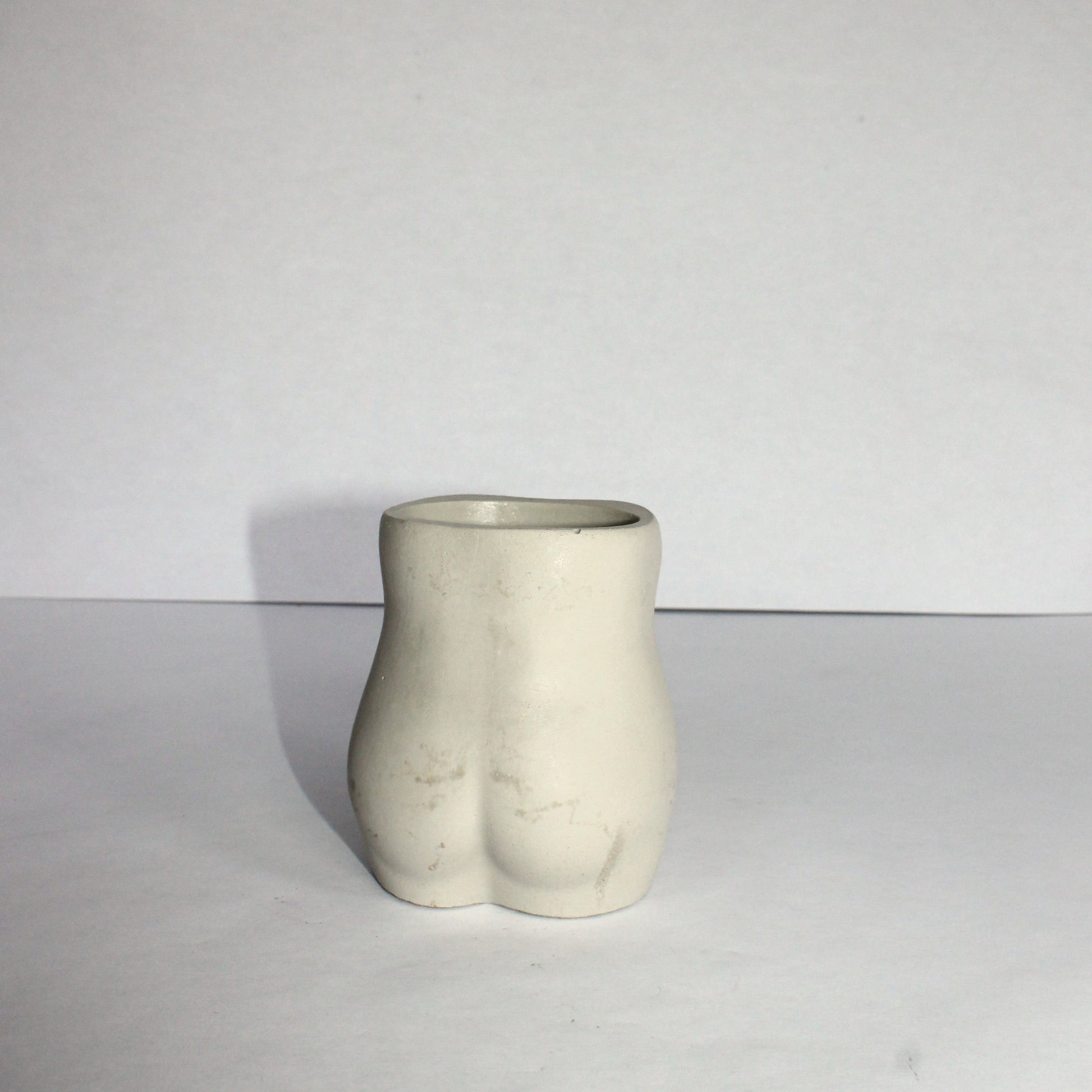Concrete vase shaped like a female torso on a white background