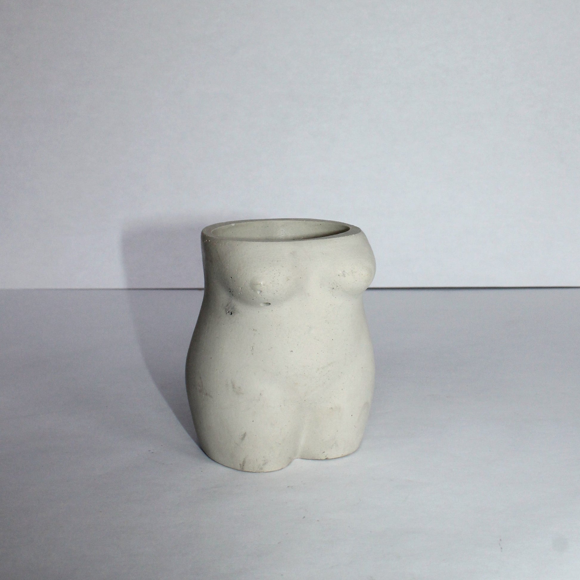 Concrete vase shaped like a female torso on a white background
