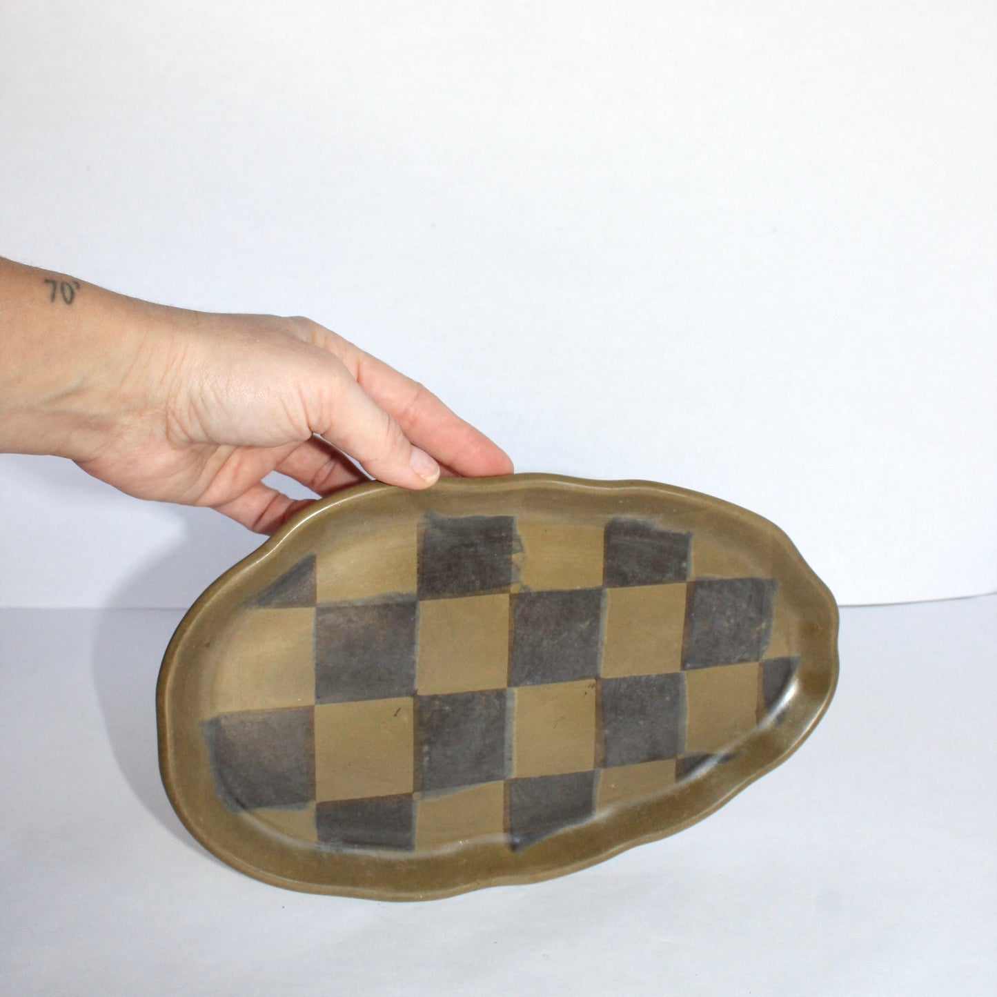 Hand holding a checkered cement plate on a white background