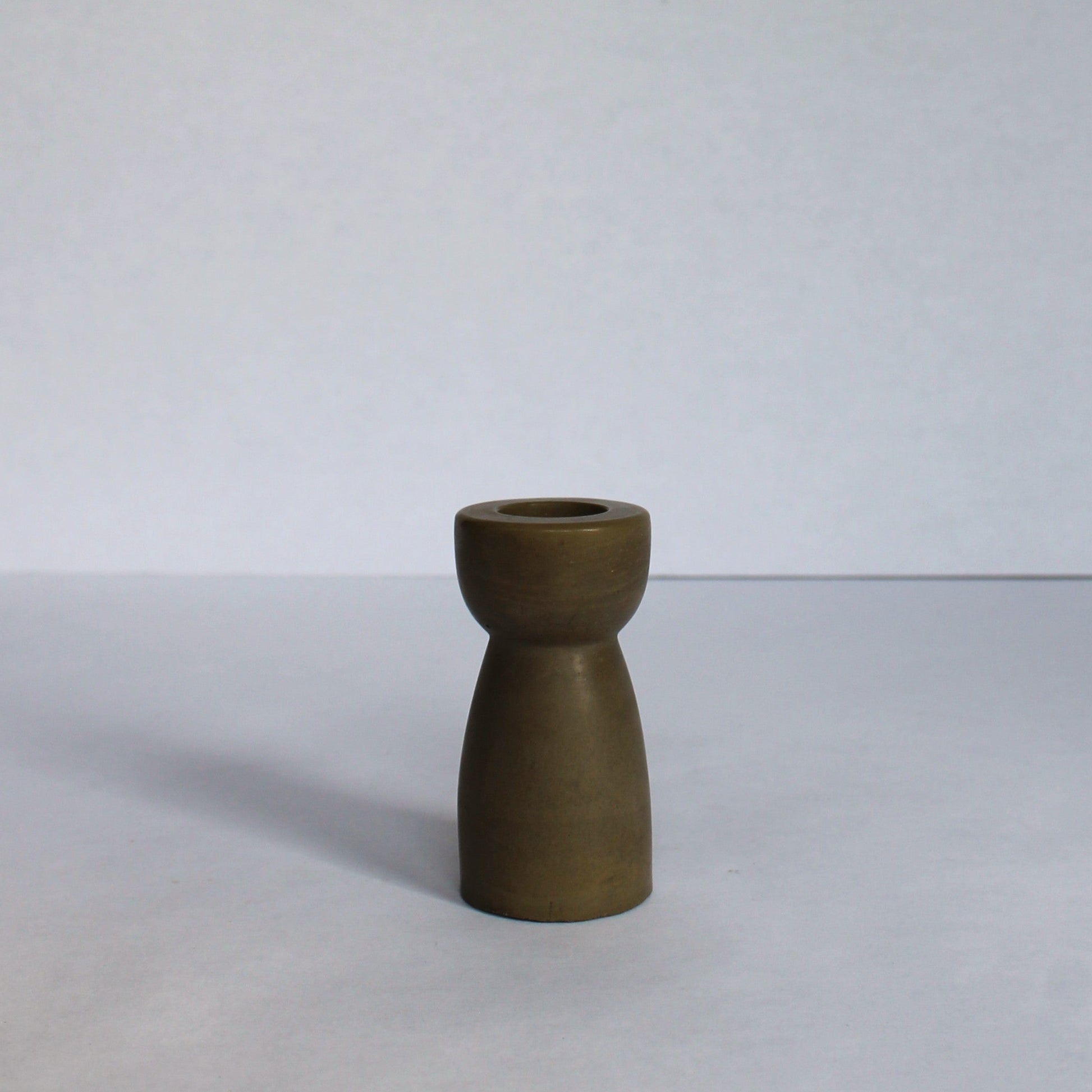 Small green concrete candle stick holder on a white background
