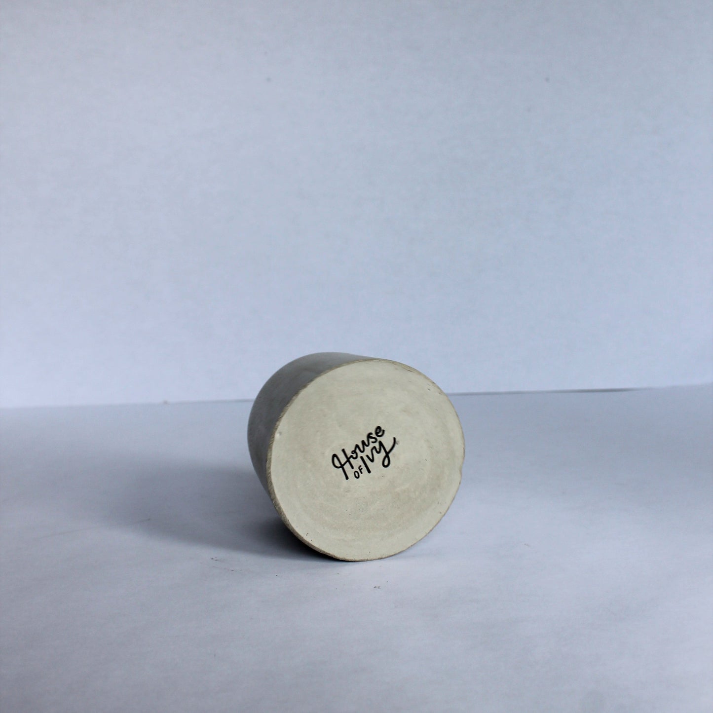 bottom of round concrete pot with House of Ivy branding on a white background