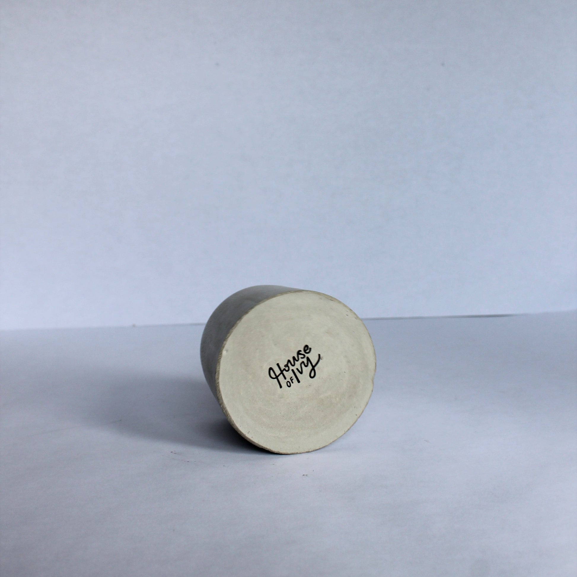 bottom of round concrete pot with House of Ivy branding on a white background