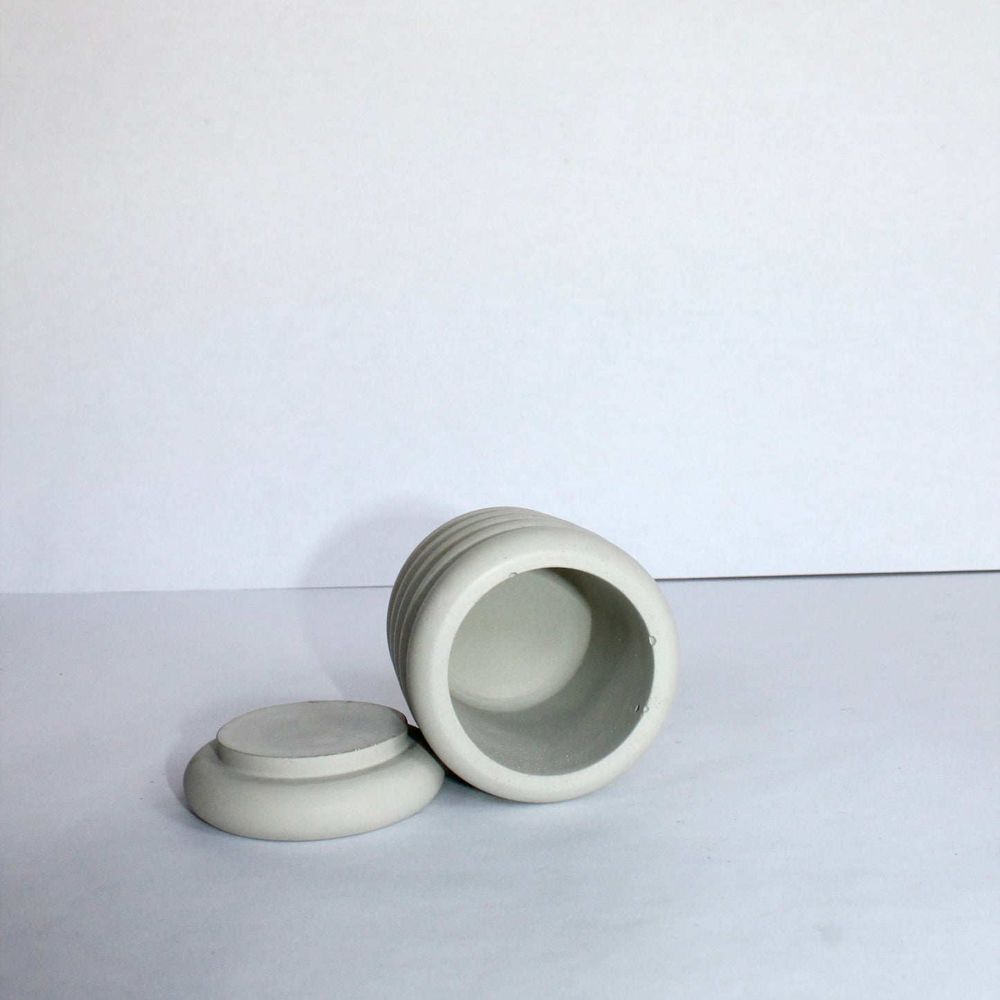 Inside view of light gray concrete jar with lid on a white background