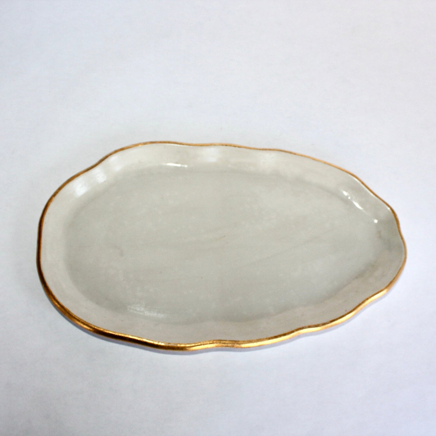 Light gray concrete plate with gold rim on a white background