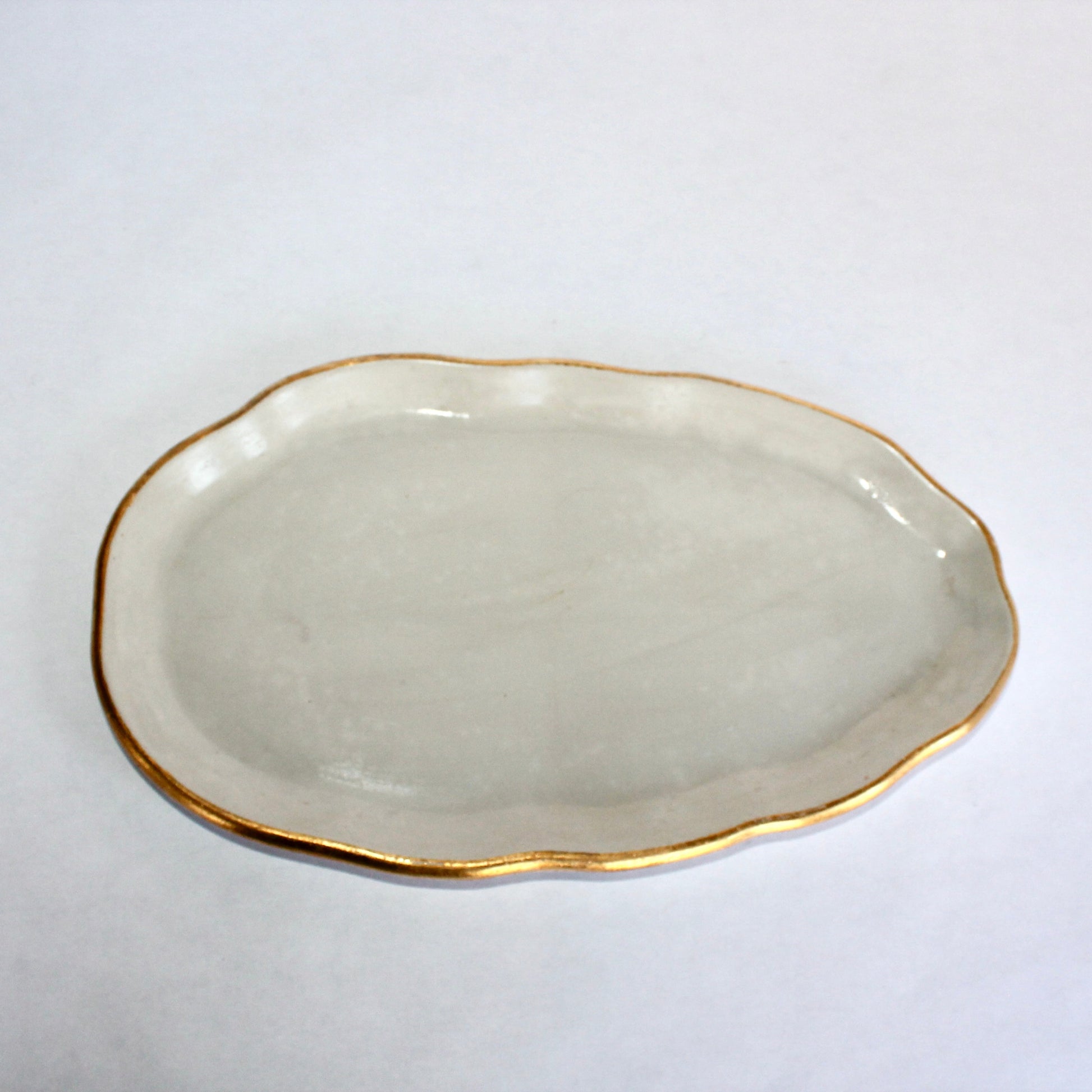 Light gray concrete plate with gold rim on a white background