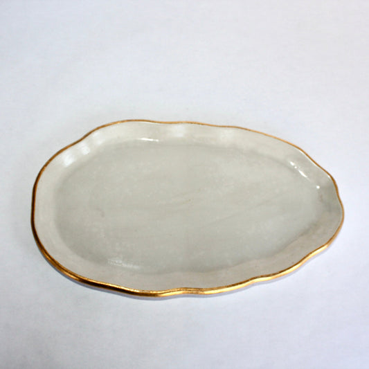 Light gray concrete plate with gold rim on a white background