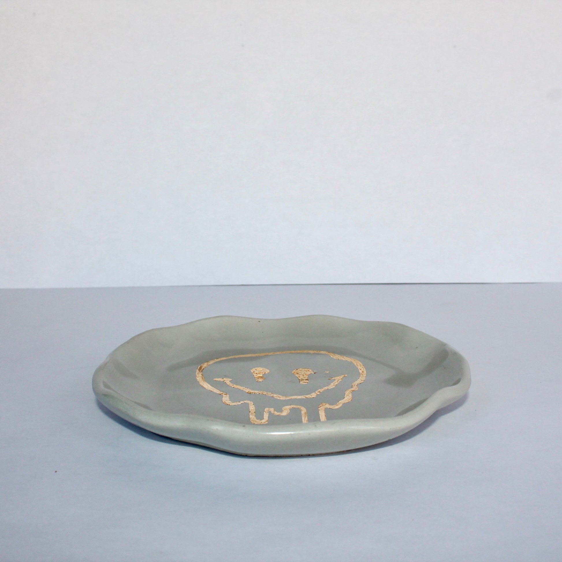 Light gray concrete plate with a smiley face design on a white background