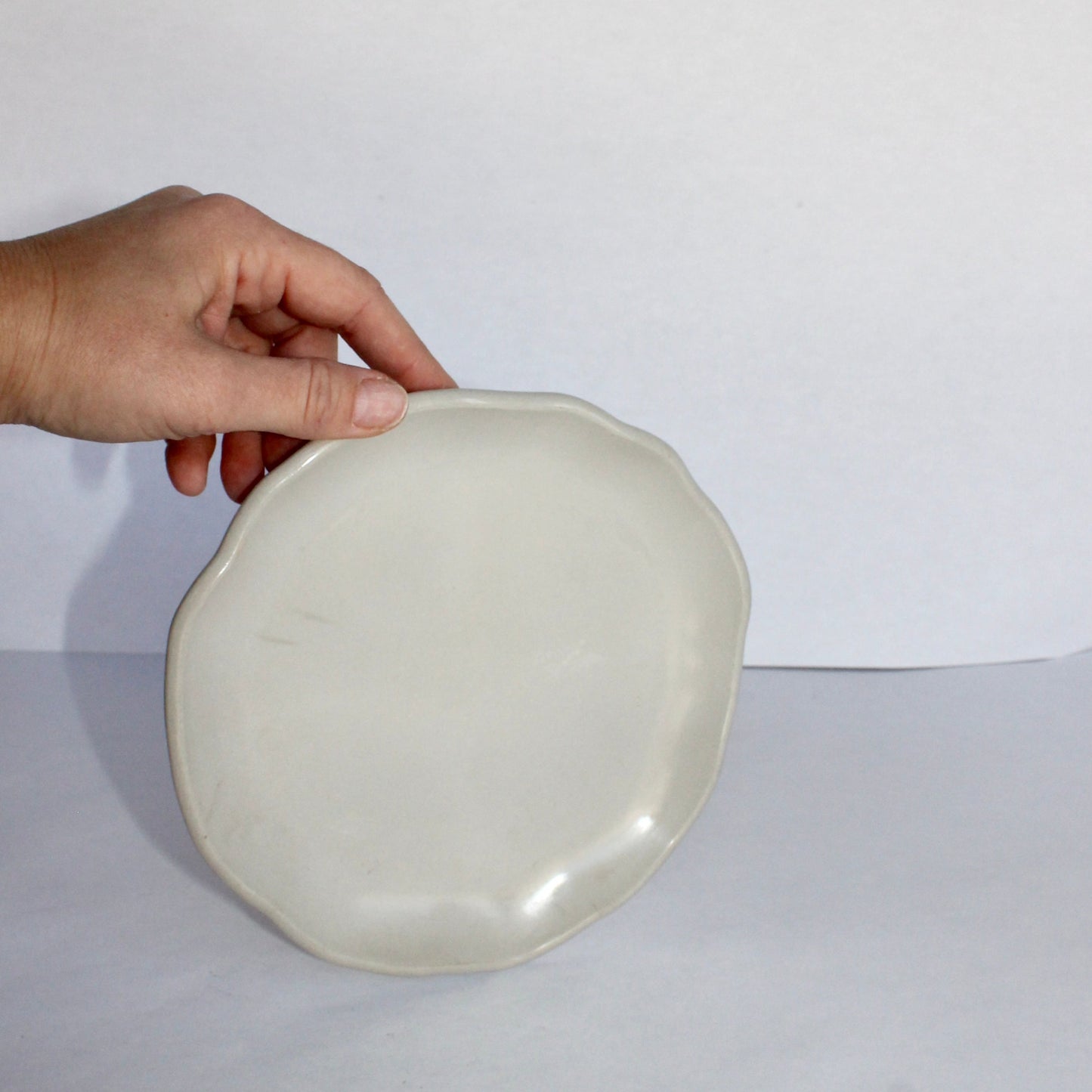 Hand holding a light gray concrete plate against a plain background