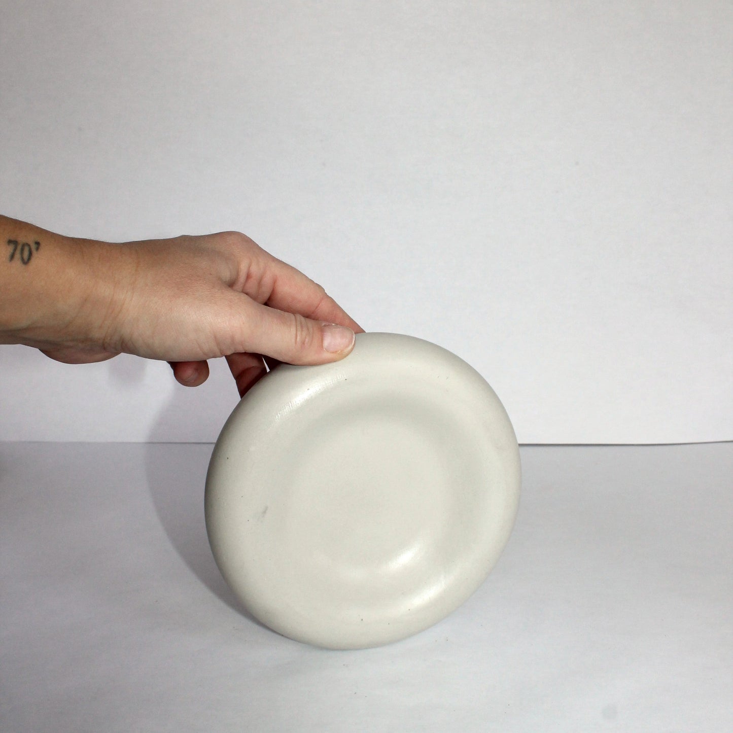 Hand holding a light gray concrete tray against a plain background
