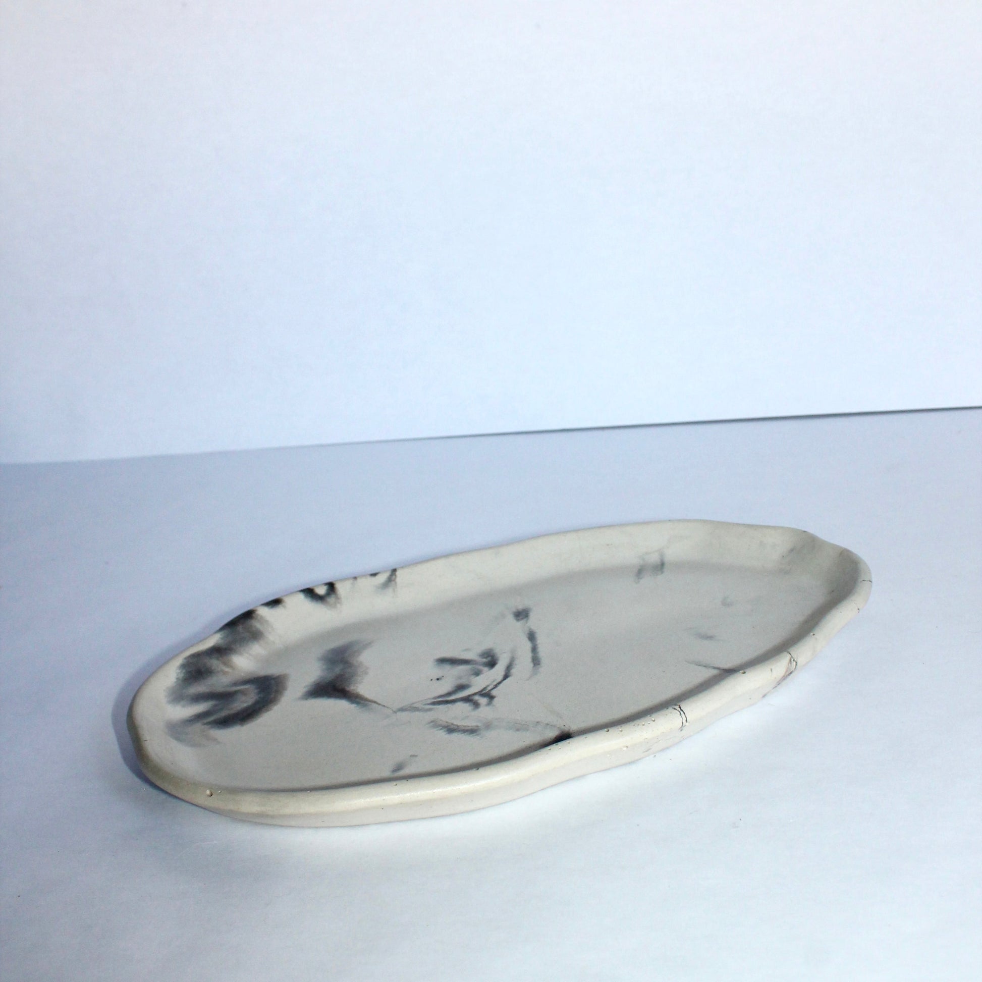 Oval concrete plate with abstract marbling design on a white background