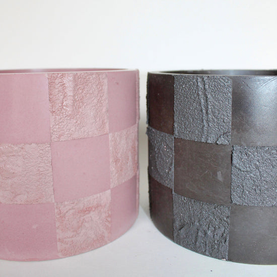 two monochromatic textured concrete checker planter pots in pink and black