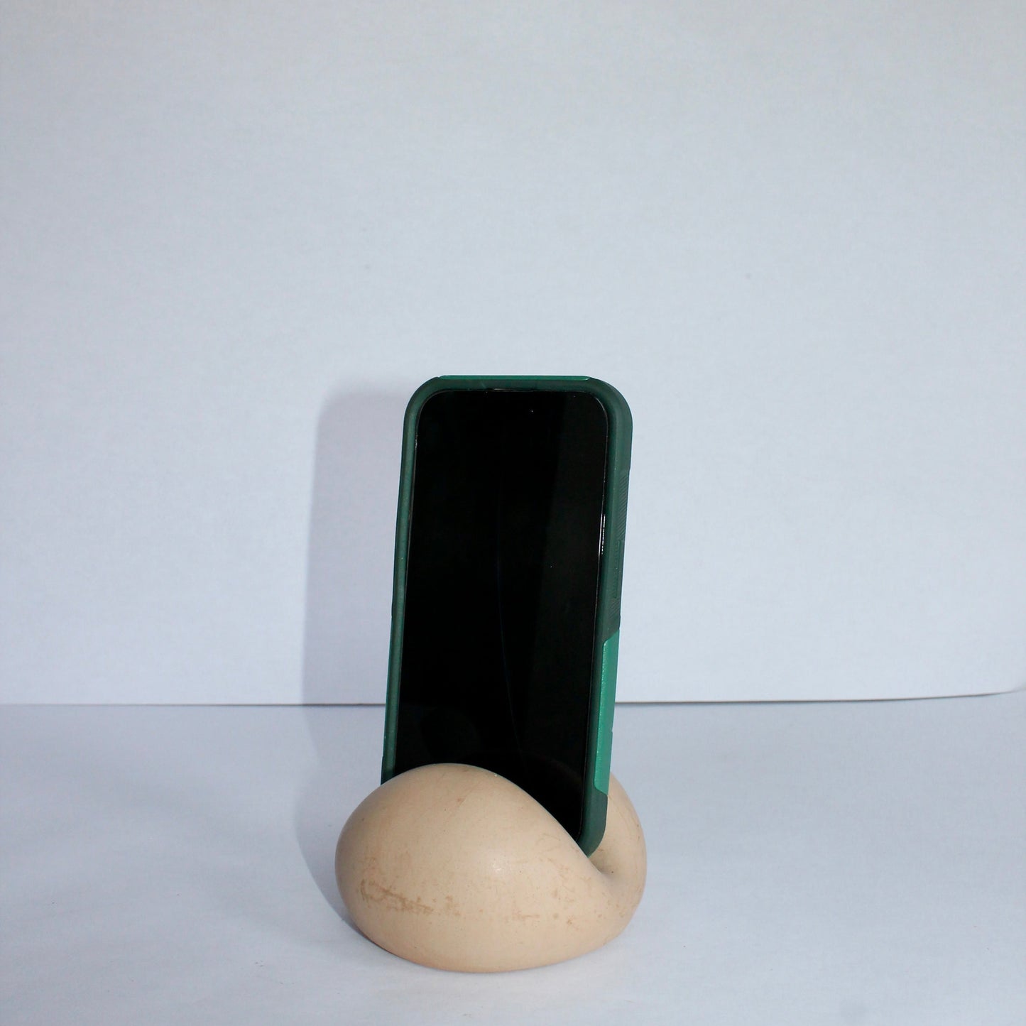 Phone stand holding a smartphone on a white surface with a white background
