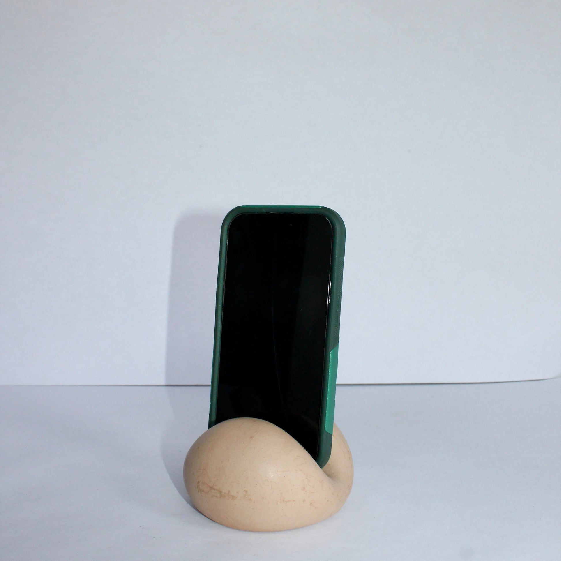 Phone stand holding a smartphone on a white surface with a white background