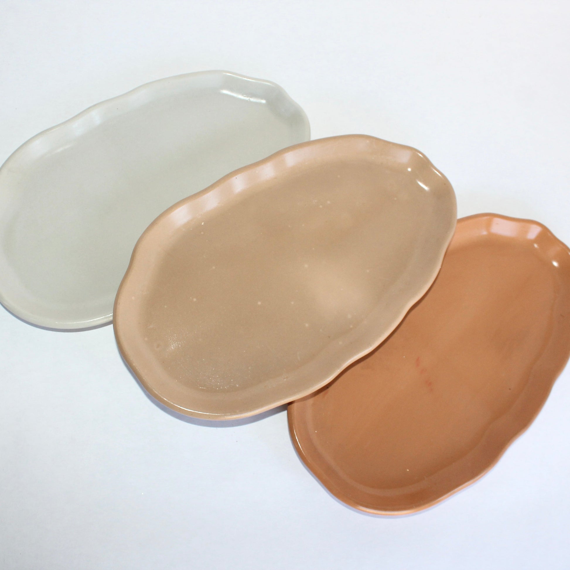 Three concrete plates in beige, terracotta, and gray on a white background