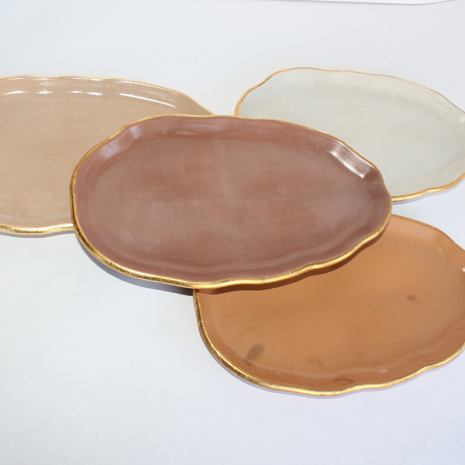 Four concrete decorative plates in different neutral colors on a white background