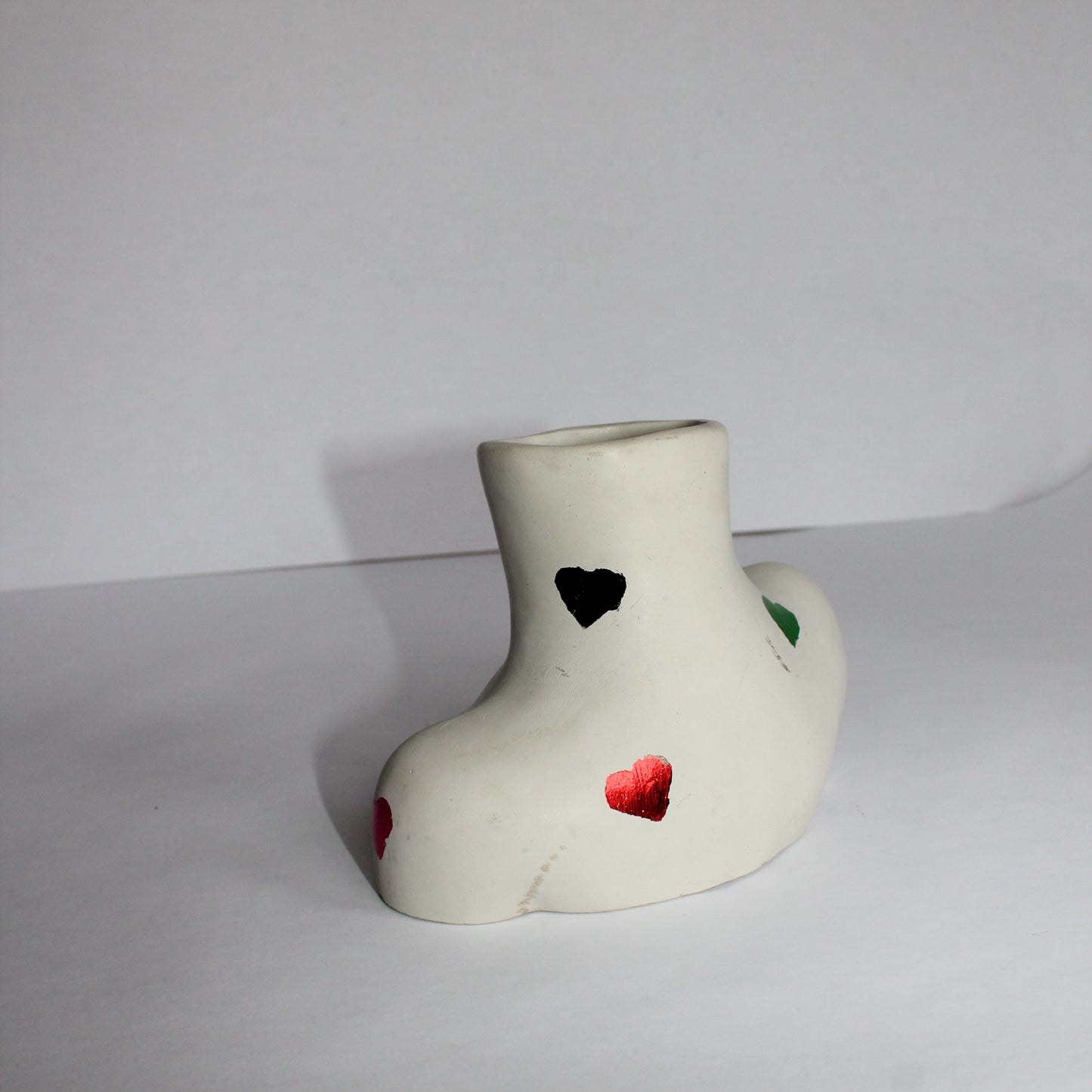 Decorative concrete object with colorful heart designs on a white background
