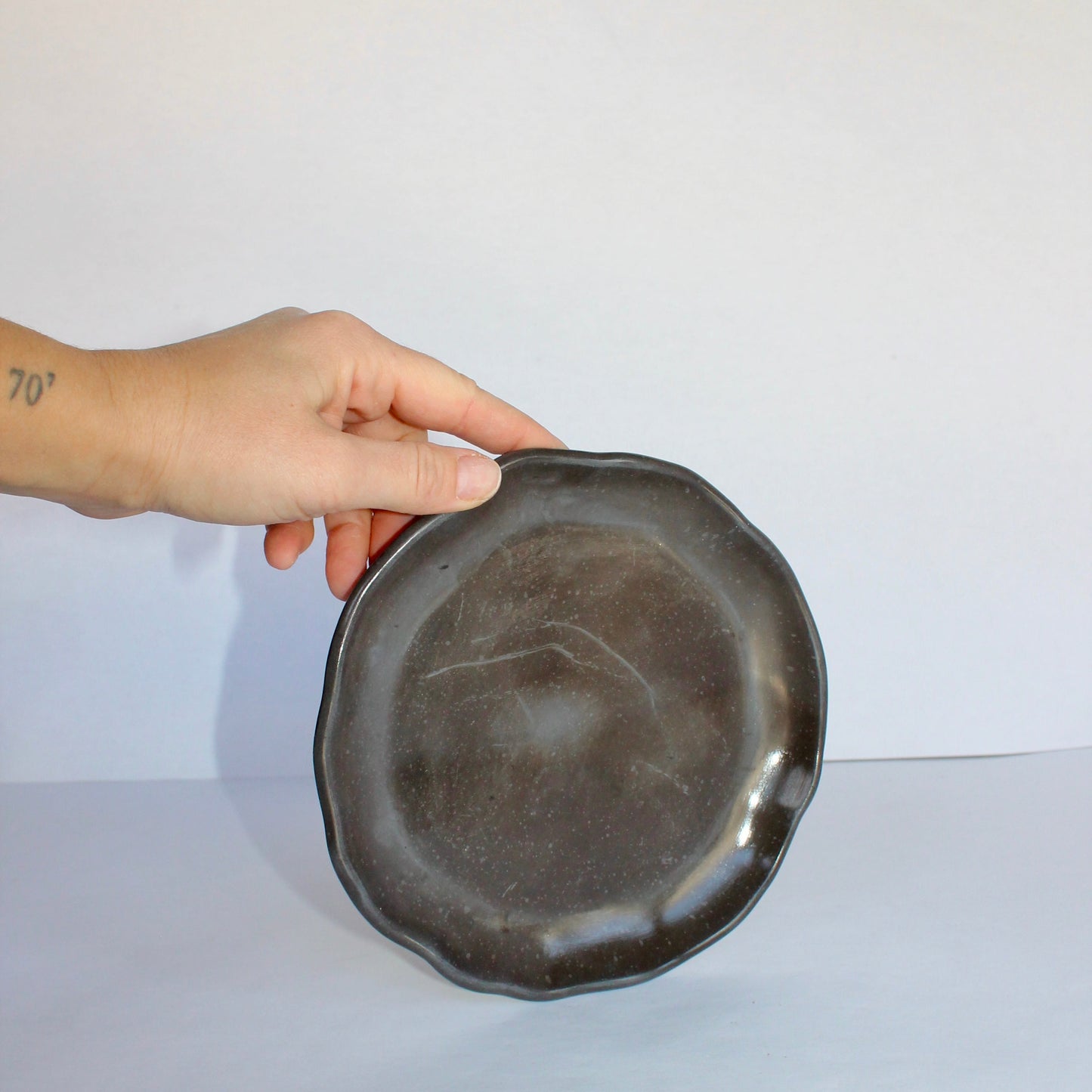 Hand holding a dark gray concrete plate against a white background