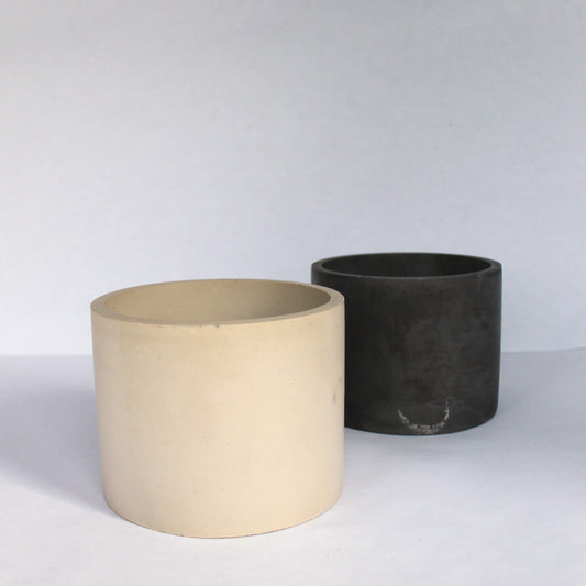 Two concrete pots, one beige and one dark gray, on a white background