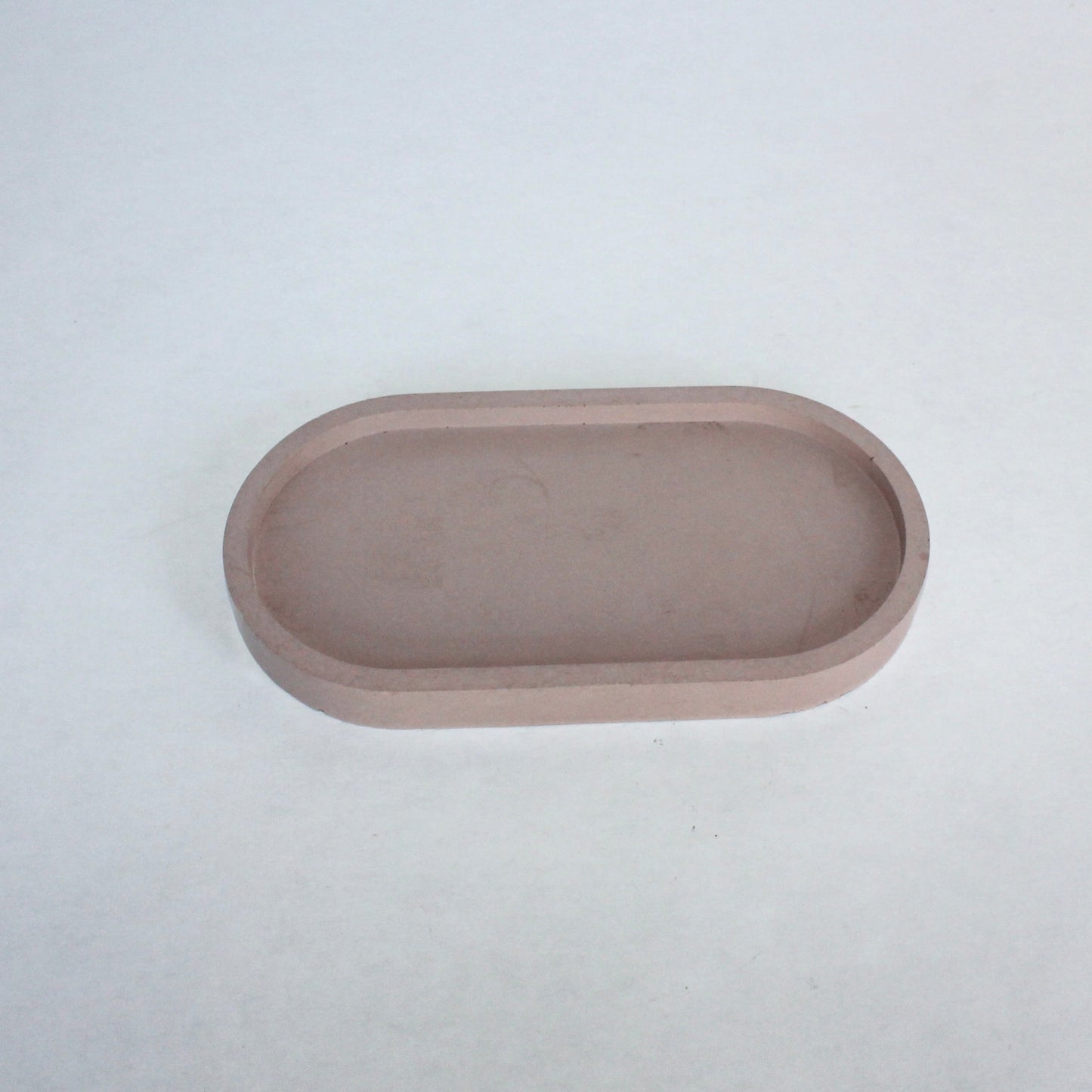 Small pale pink oval cement tray on a white background