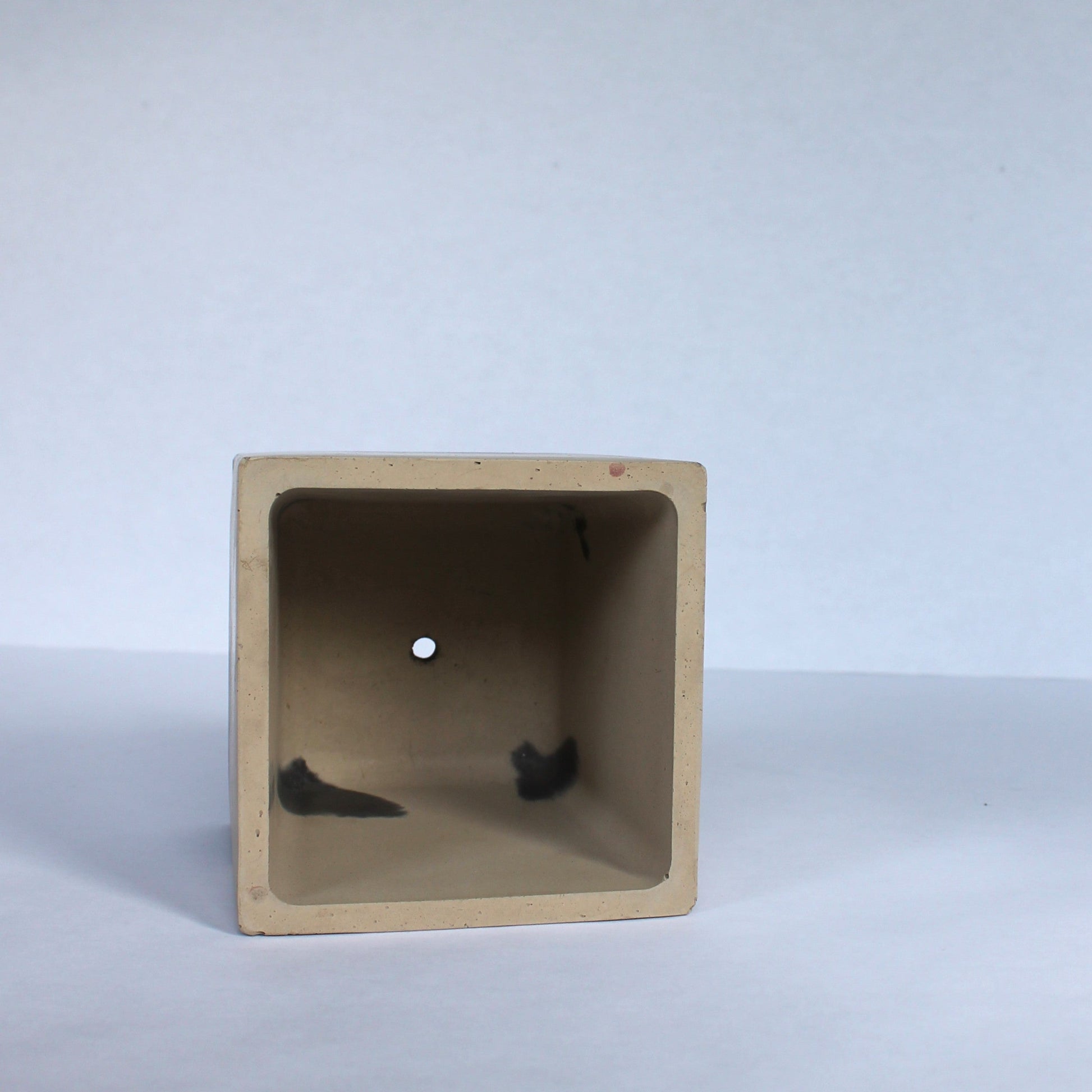 Inside view of square planter with a drainage hole on white background