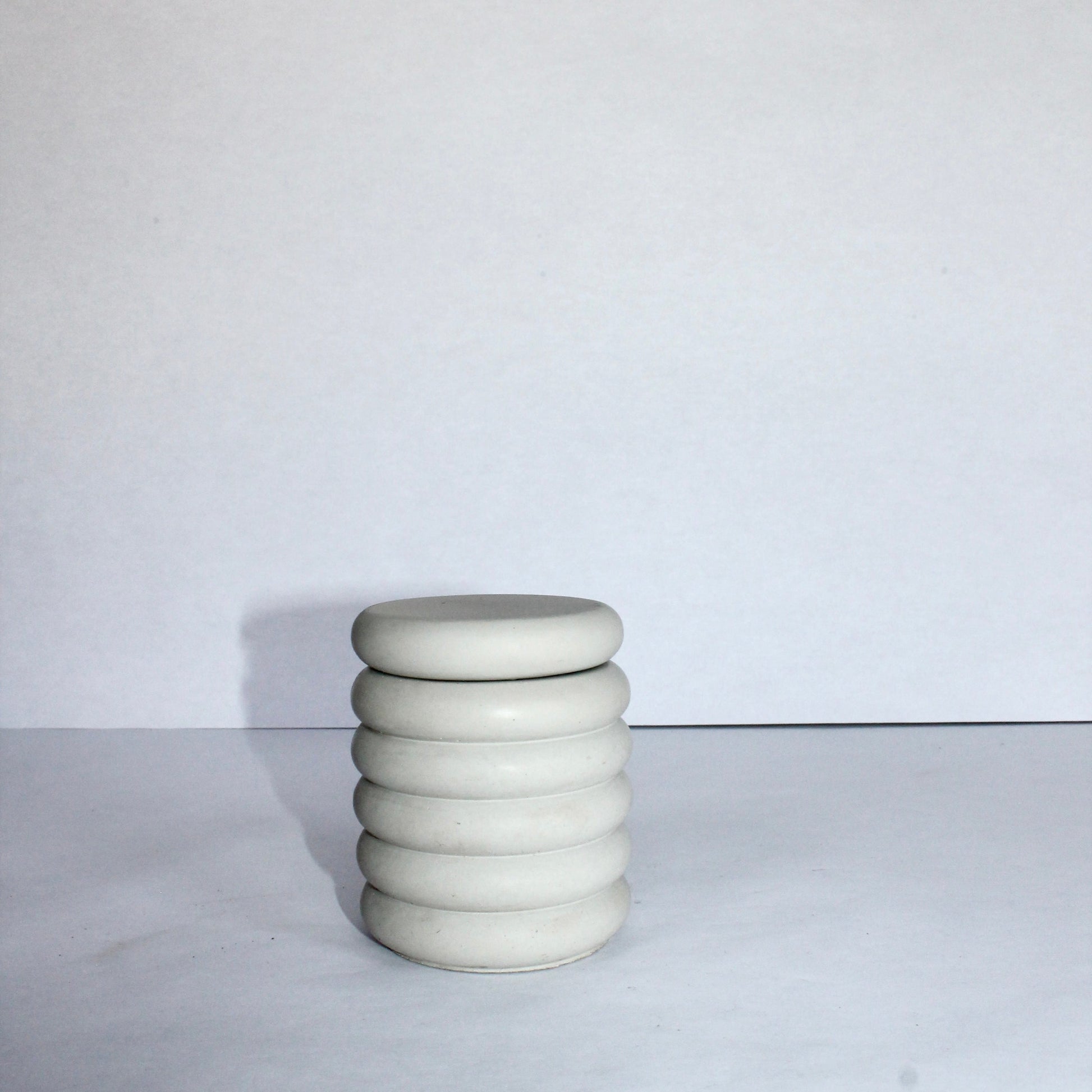 Light gray bubble jar with lid on, on a white surface with a white background