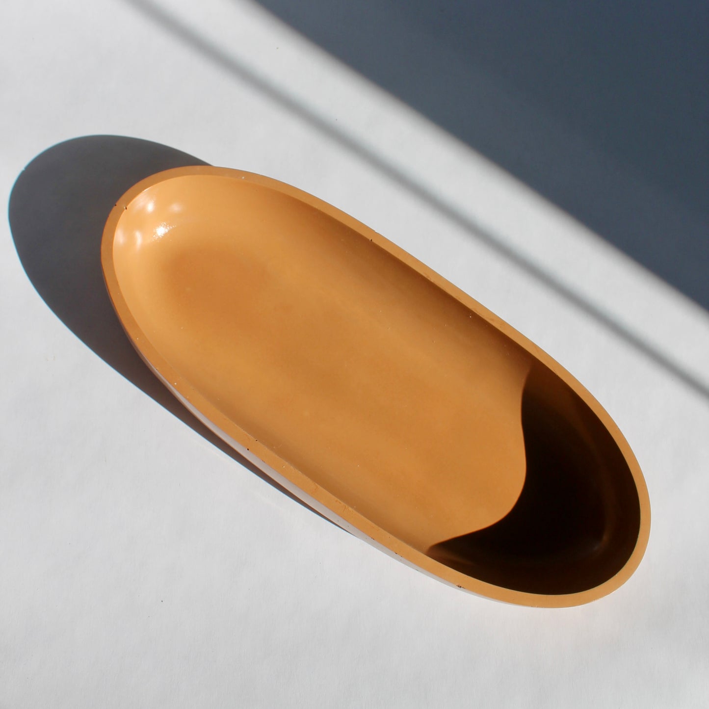 terracotta colored oval bowl on white background